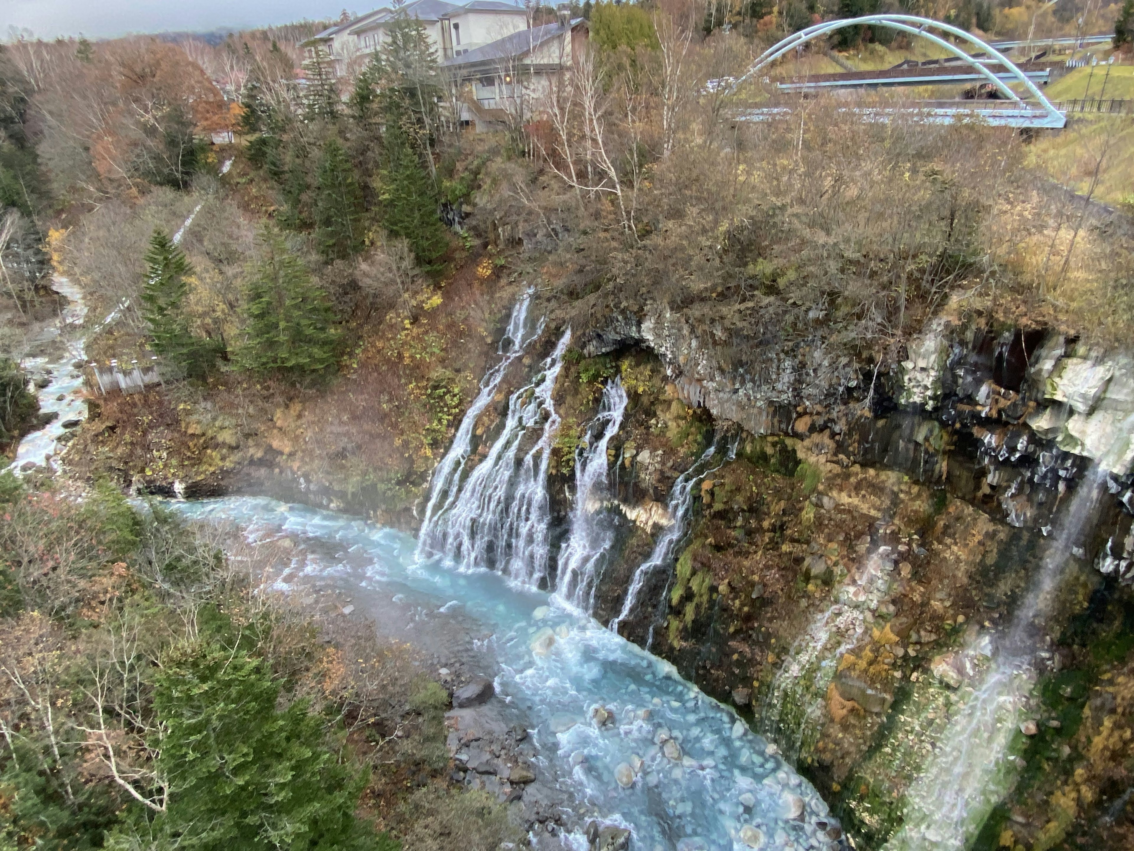 Vista panoramica di una cascata con un ponte in un ambiente naturale