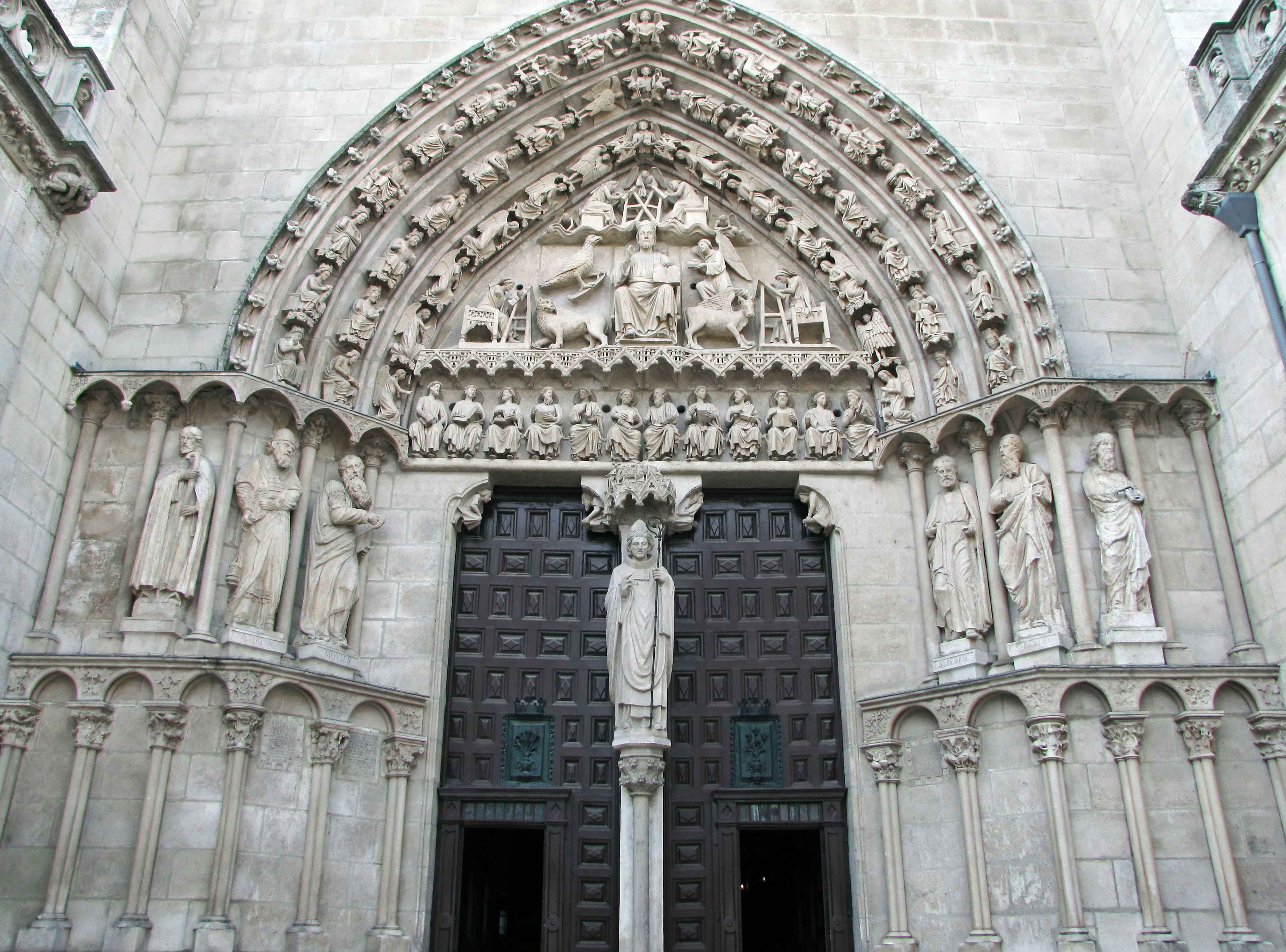 Gothic church facade with intricate sculptures featuring large doors and saint figures