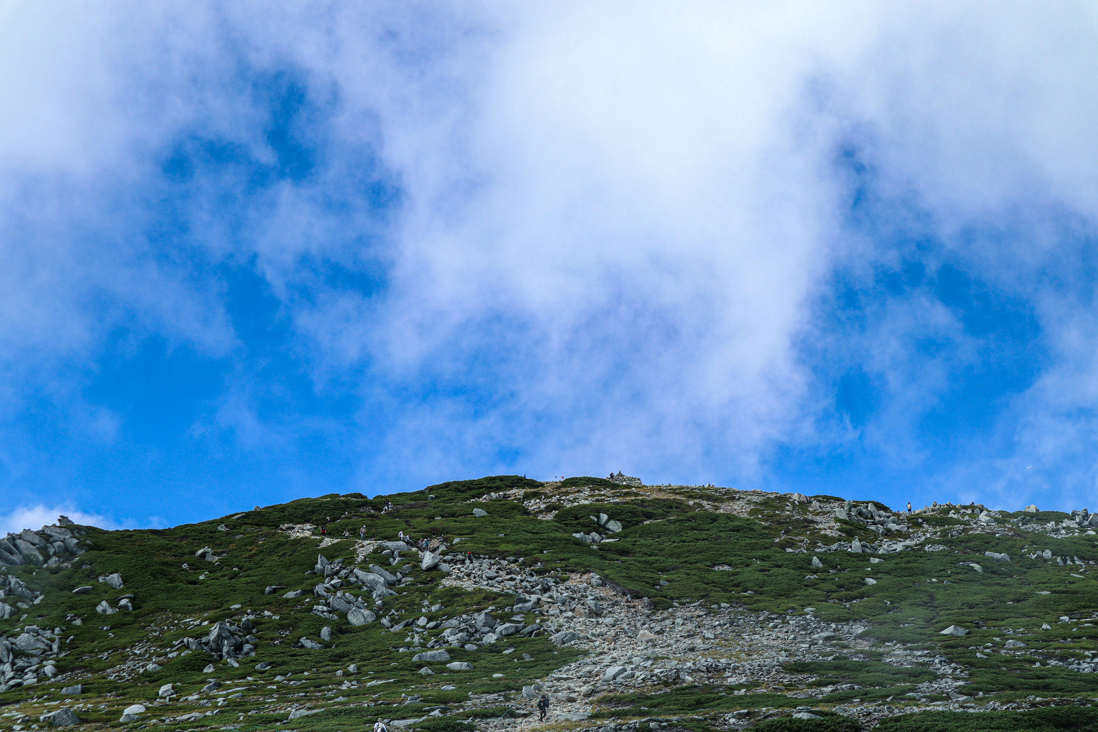 Montaña verde bajo un cielo azul con nubes