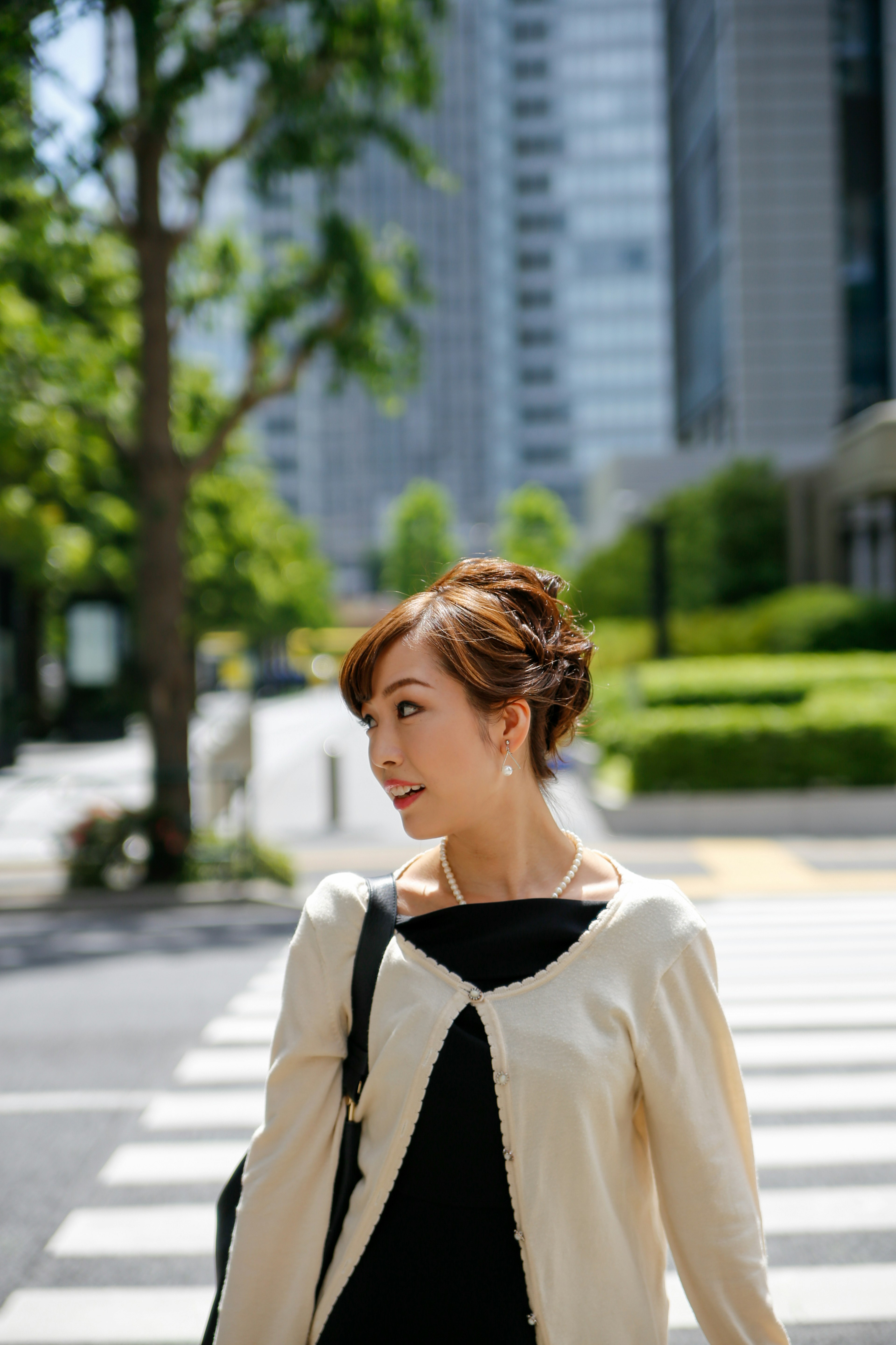 Portrait of a woman walking in the city with green trees and skyscrapers in the background