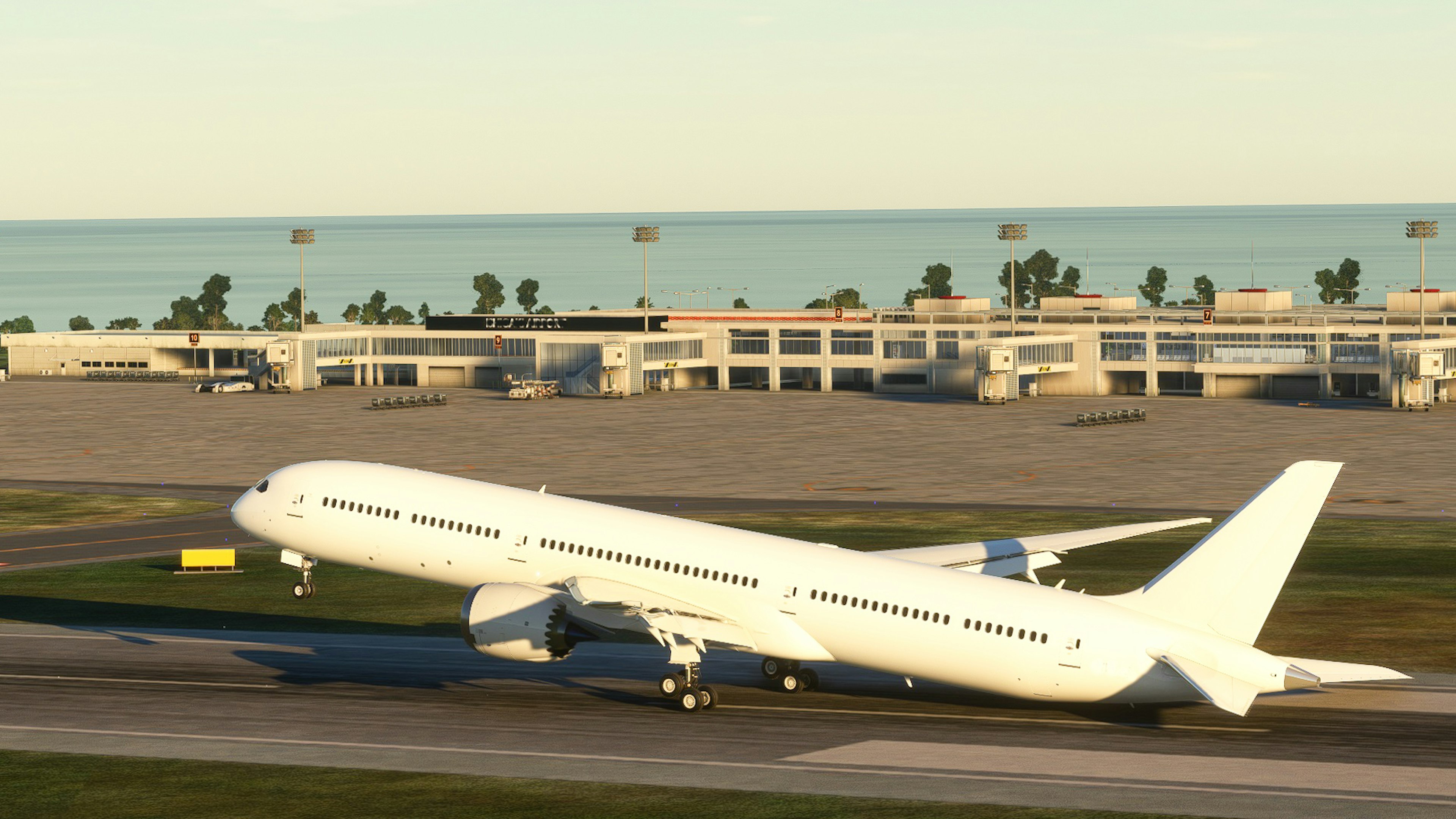 White airplane taking off from runway near the ocean at sunset