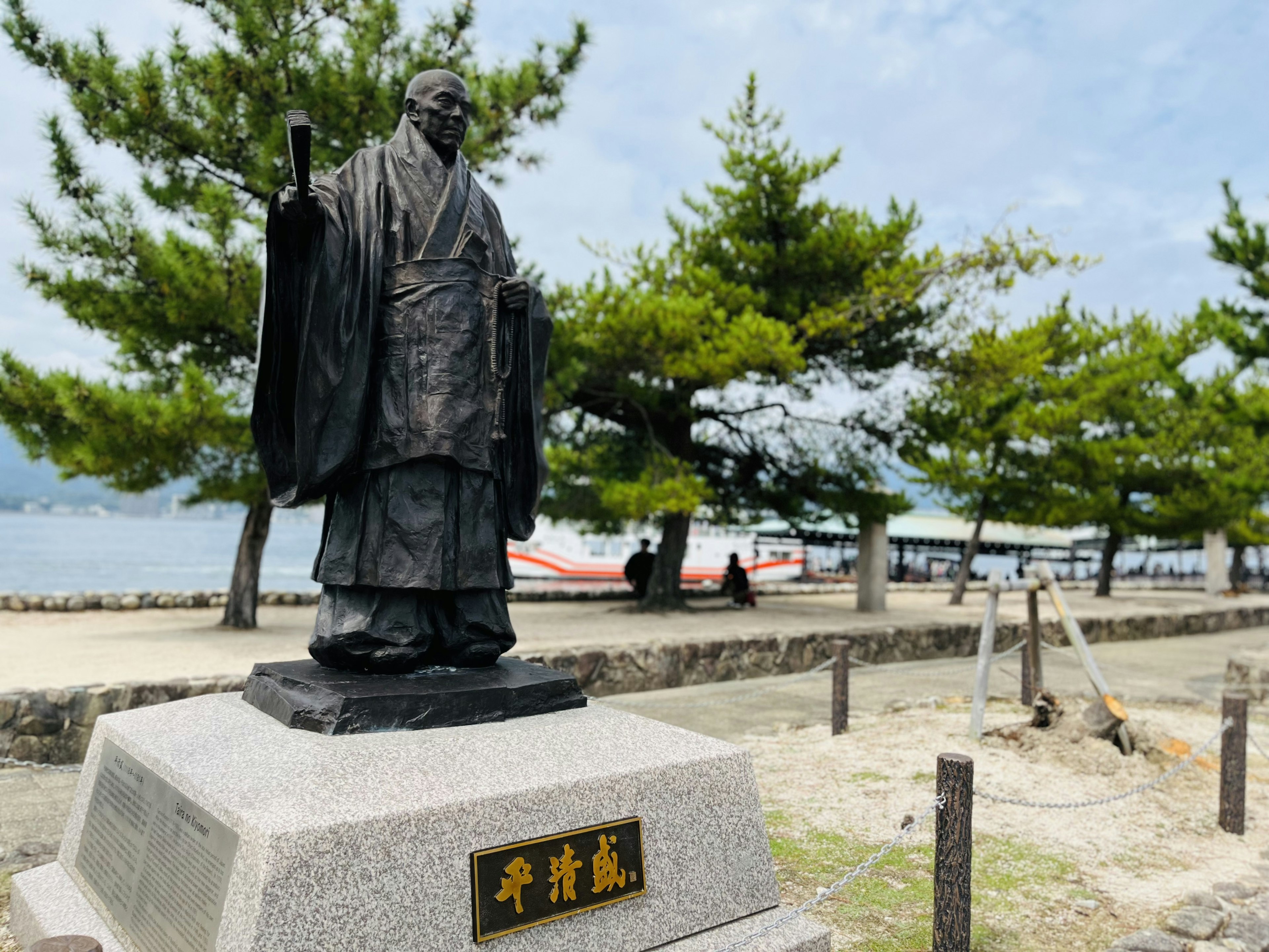 海のそばに立つ銅像の風景 緑の木々と青い空の背景