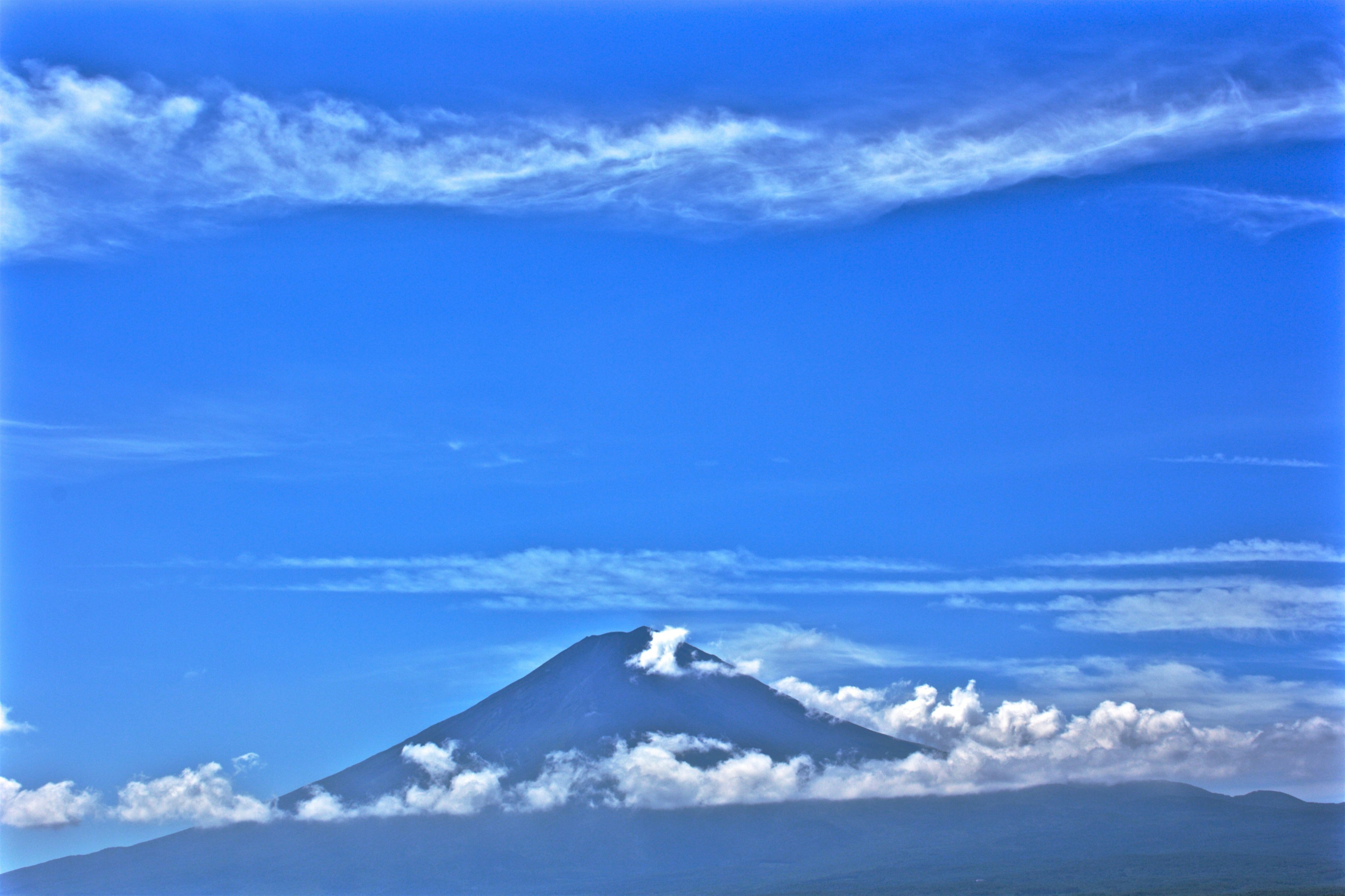 Mountain above clouds under blue sky