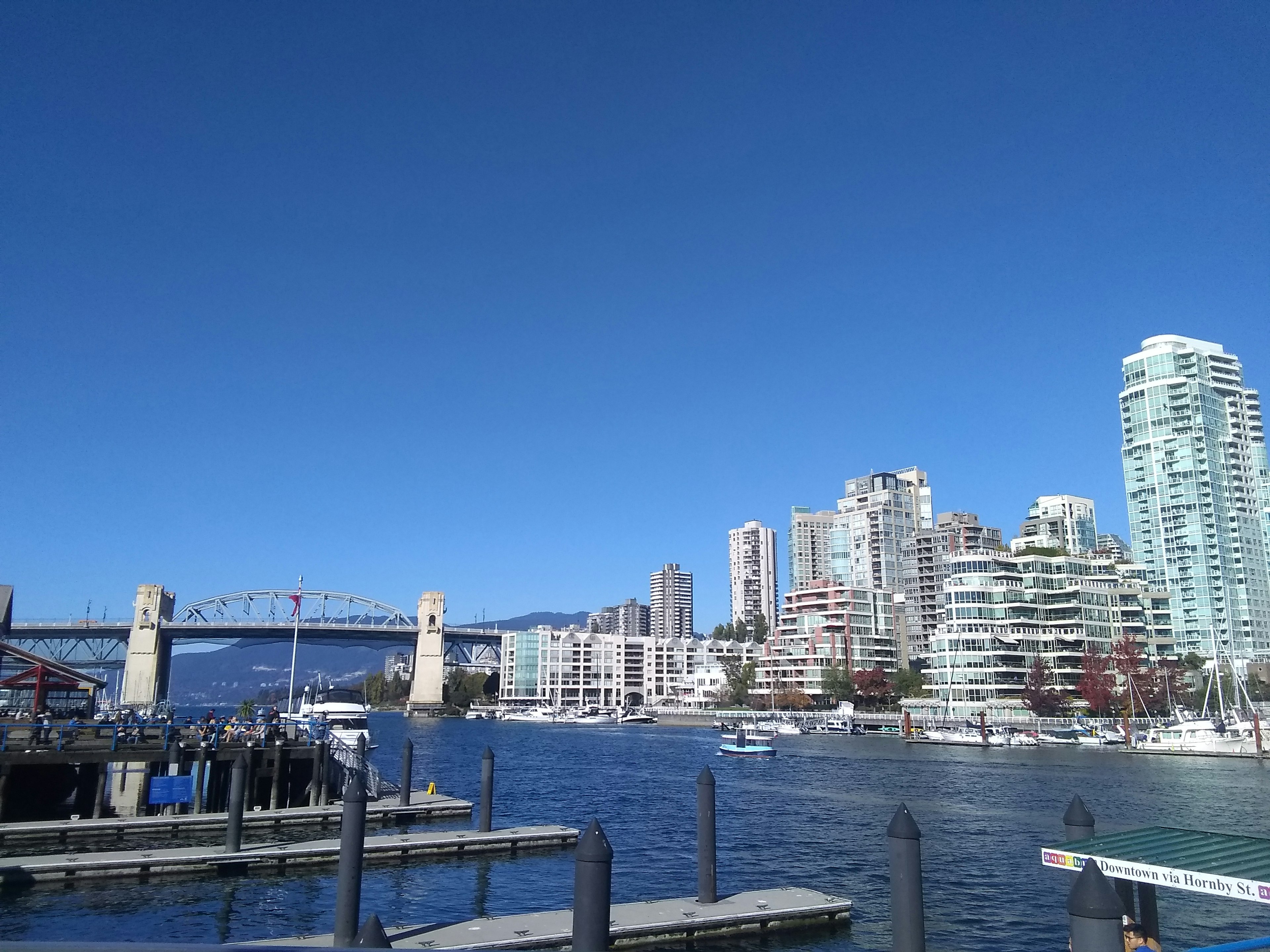 Horizonte de Vancouver con edificios altos y puerto bajo un cielo azul claro