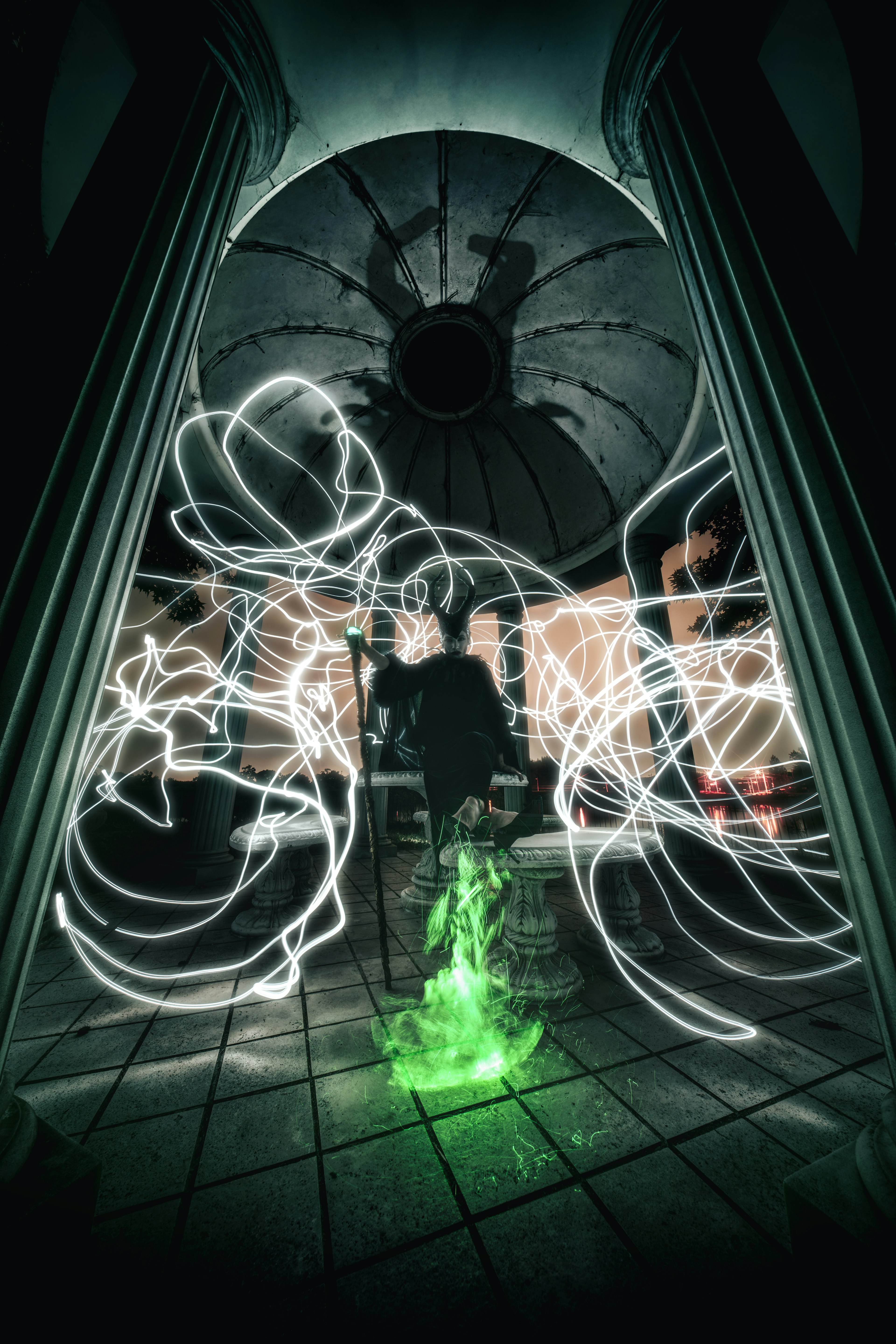 A figure standing amidst swirling green light and white trails in a dimly lit space