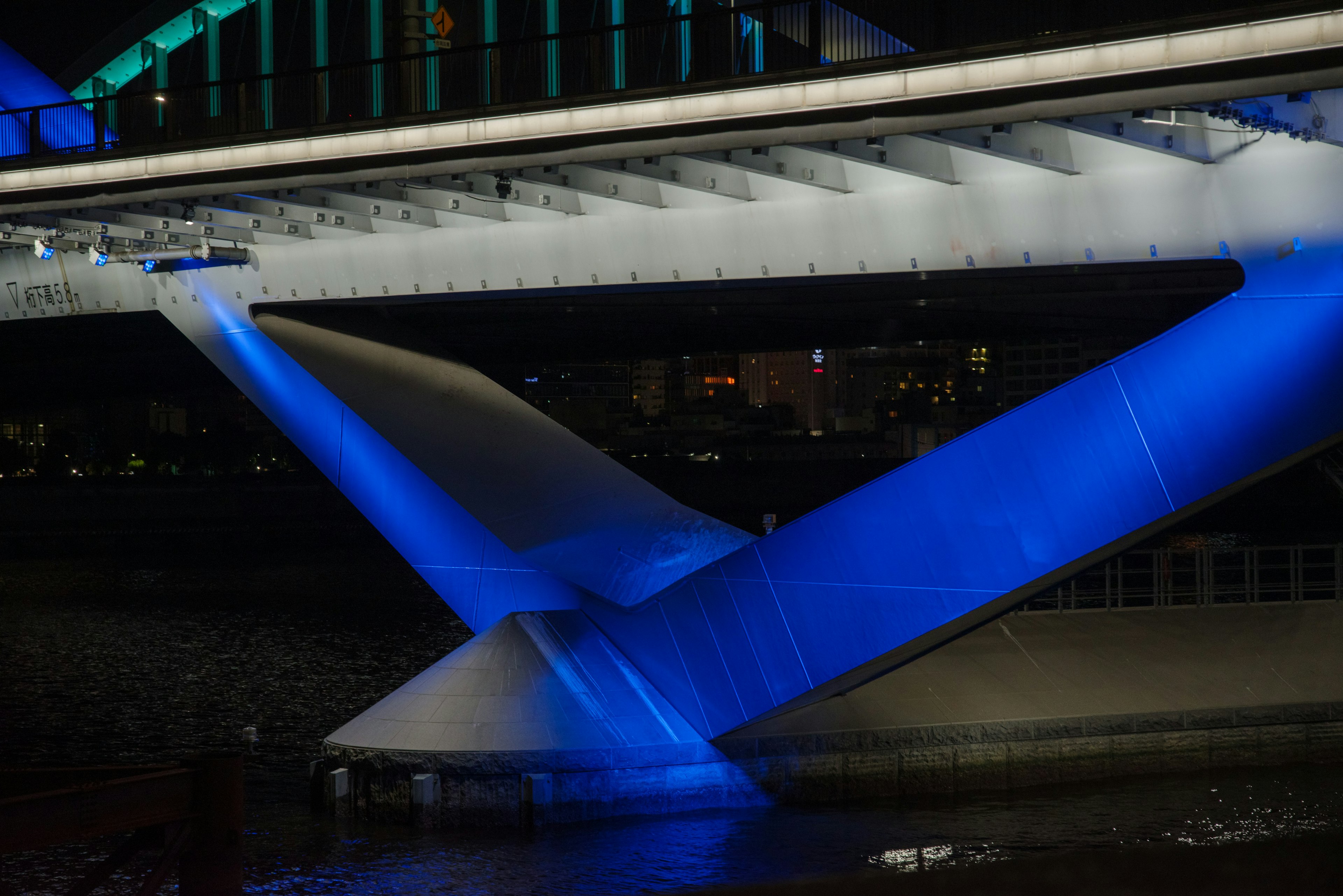 Vue détaillée de la structure sous le pont éclairée par une lumière bleue