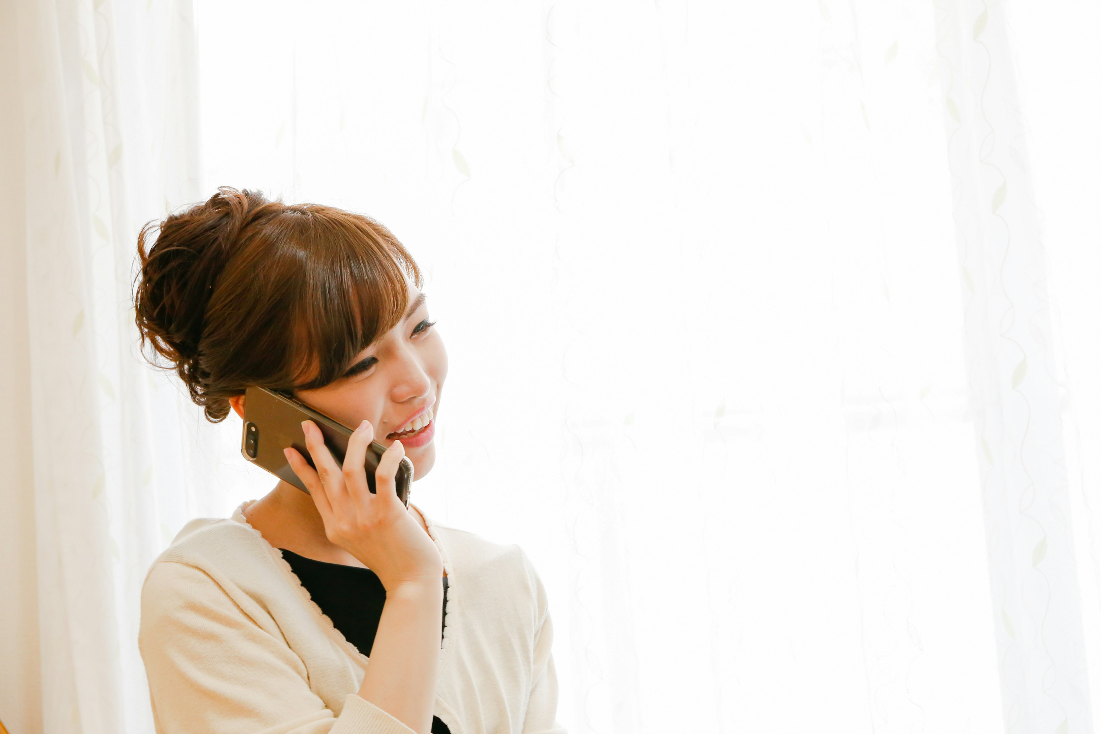 Mujer hablando por teléfono con luz brillante de ventana de fondo