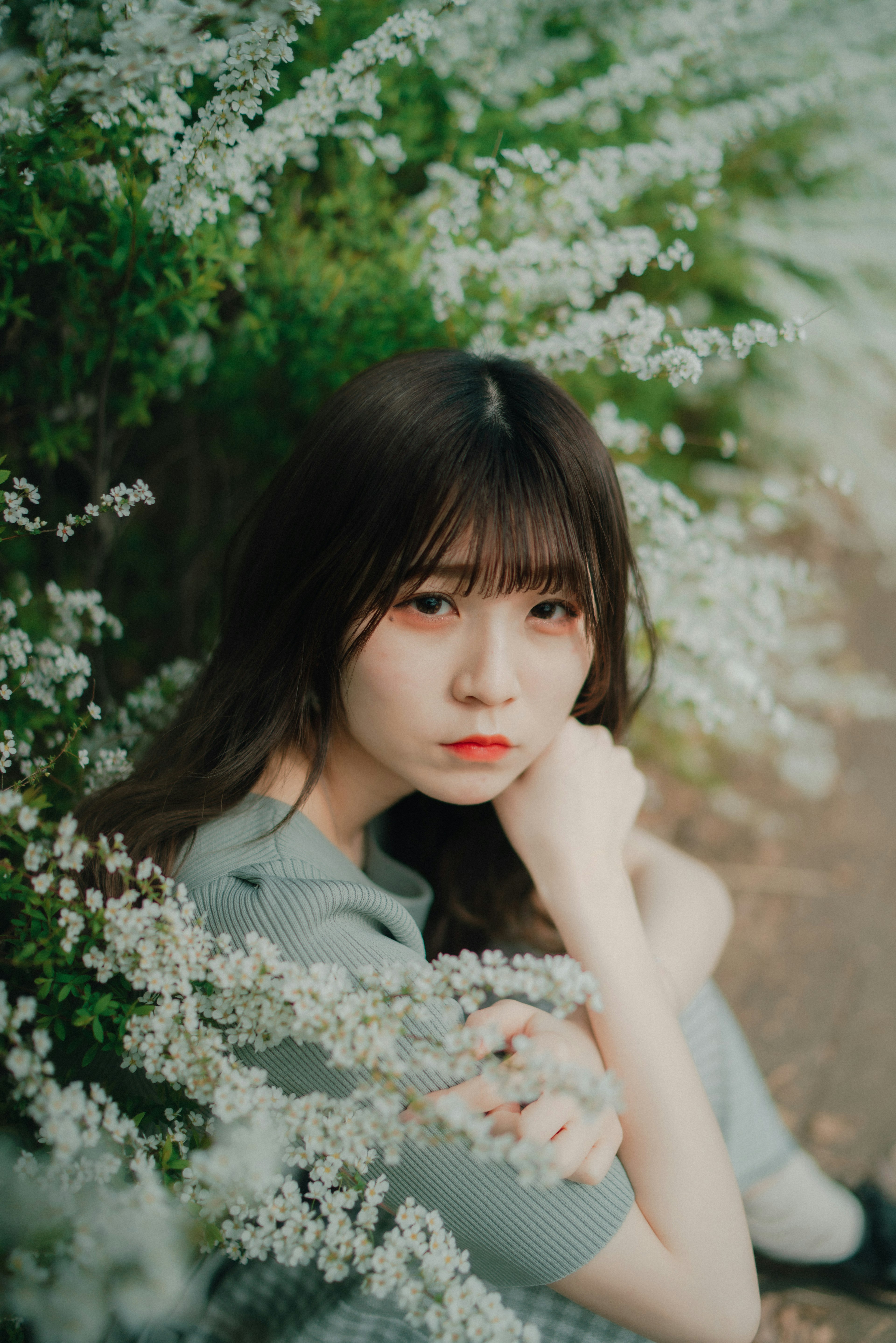 Portrait d'une femme entourée de fleurs blanches avec un air pensif