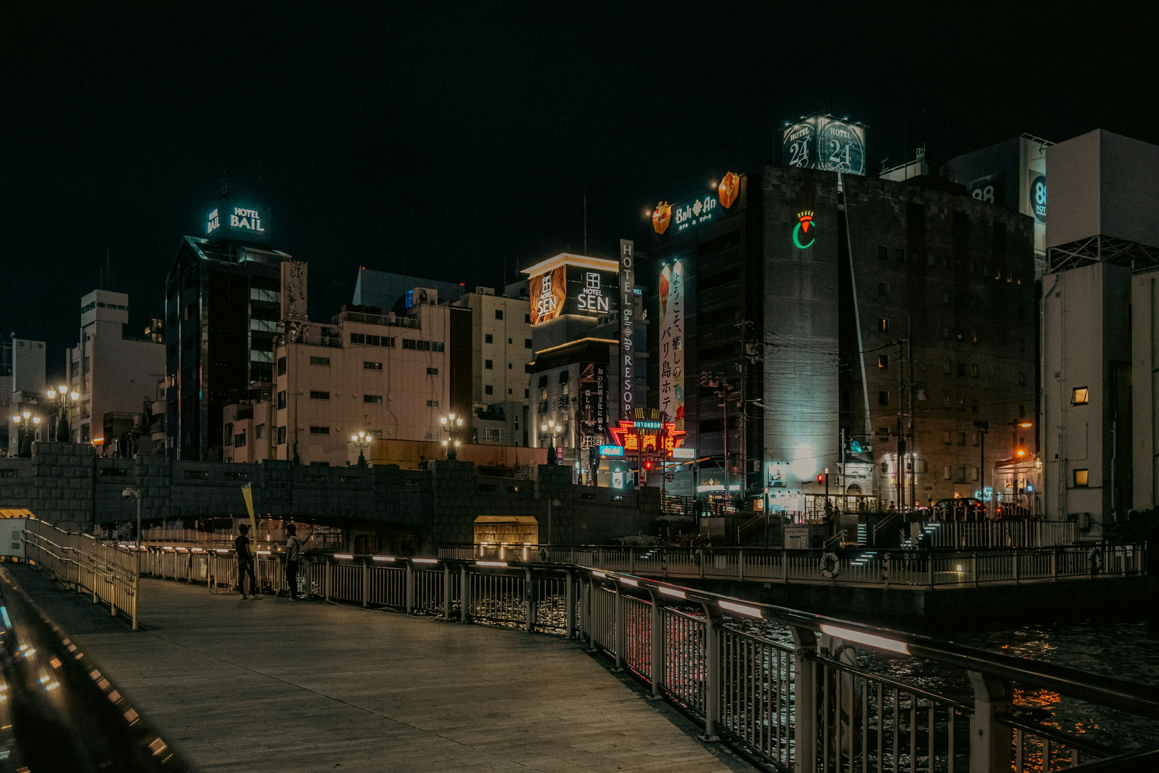 夜景の都市の風景に沿った川の遊歩道とビル群