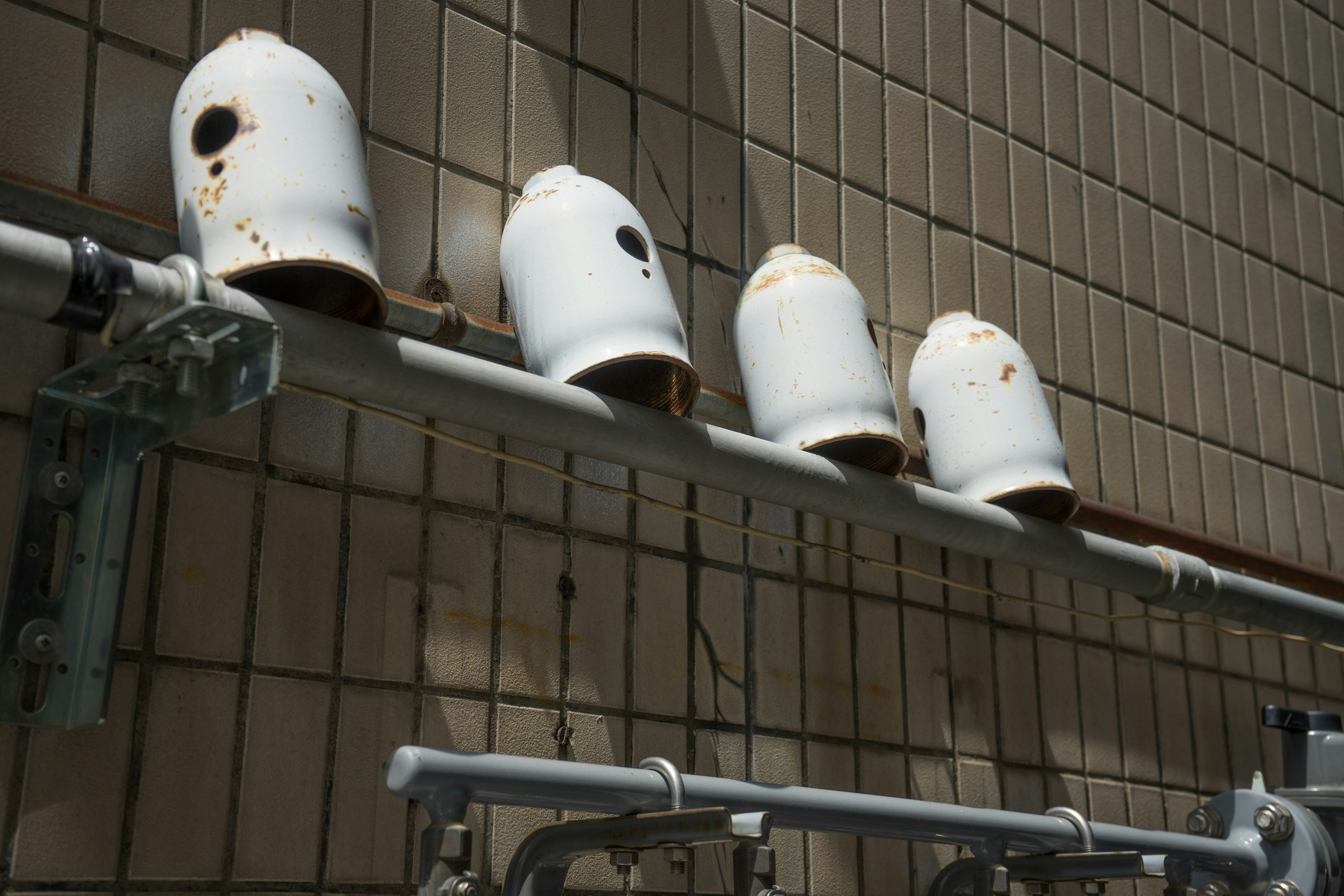 Photo of old white water tanks mounted on a pipe against a wall