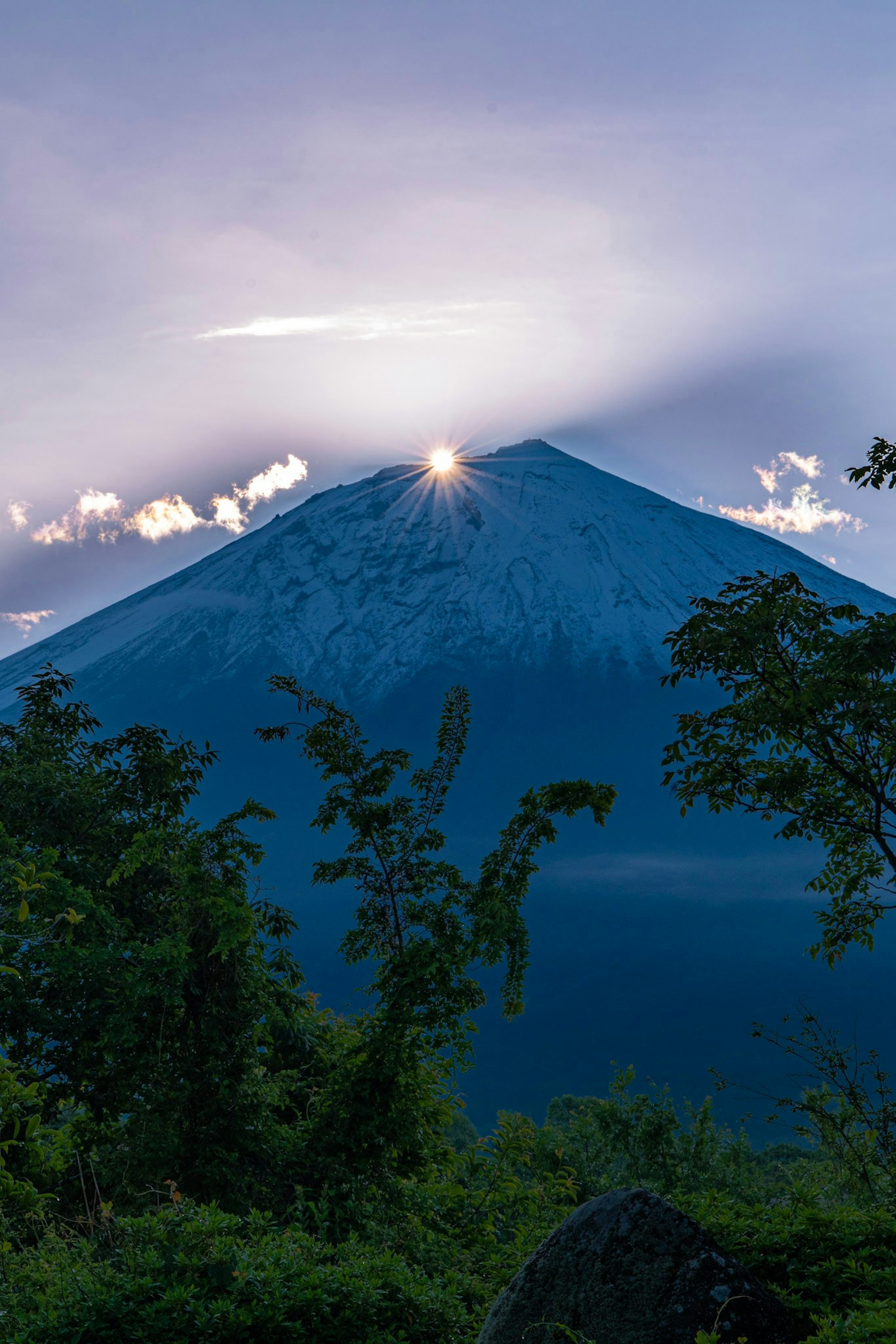 Beautiful landscape with the sun rising over a mountain peak and a blue sky