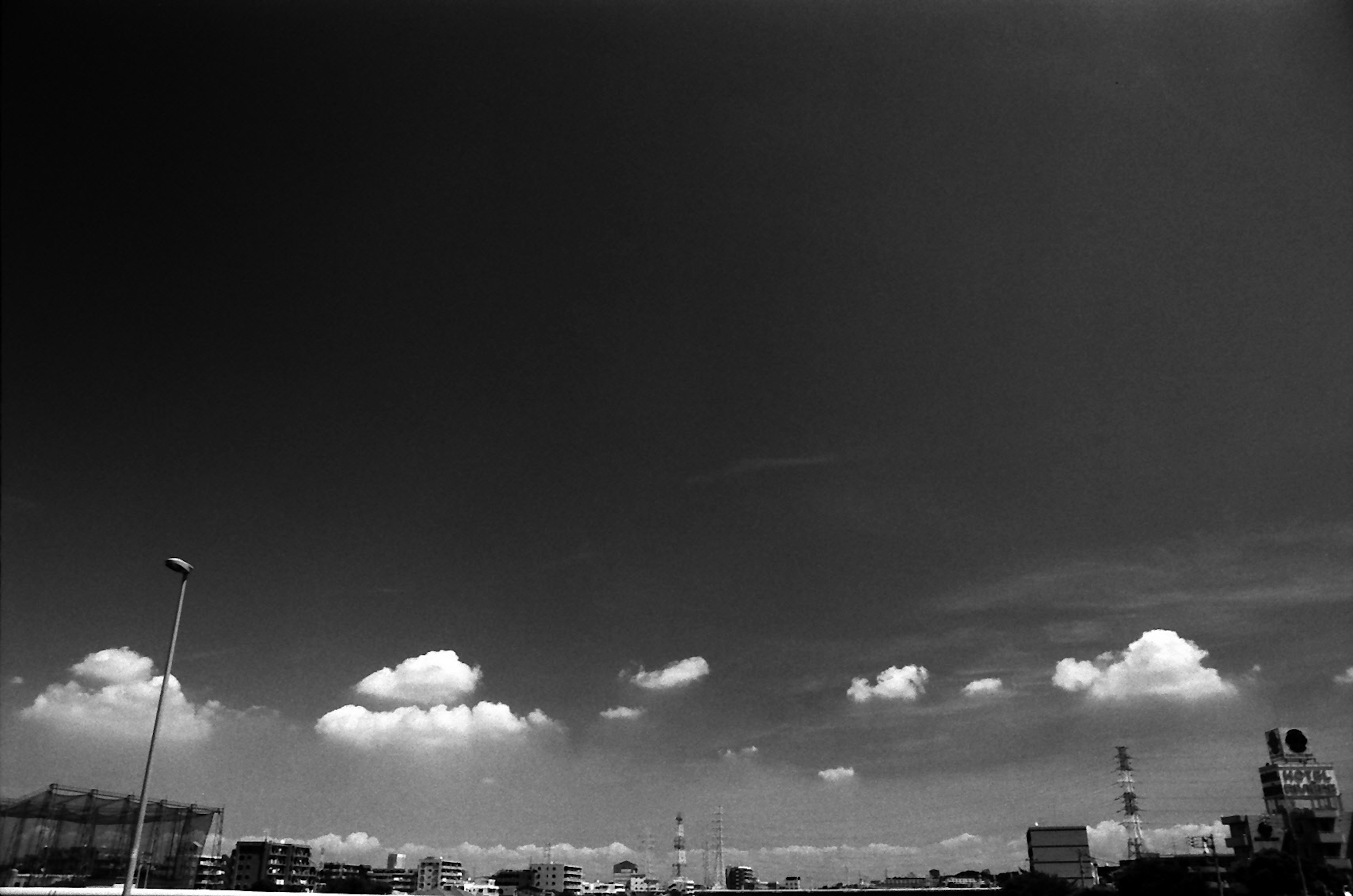 Black and white landscape featuring white clouds and city silhouettes