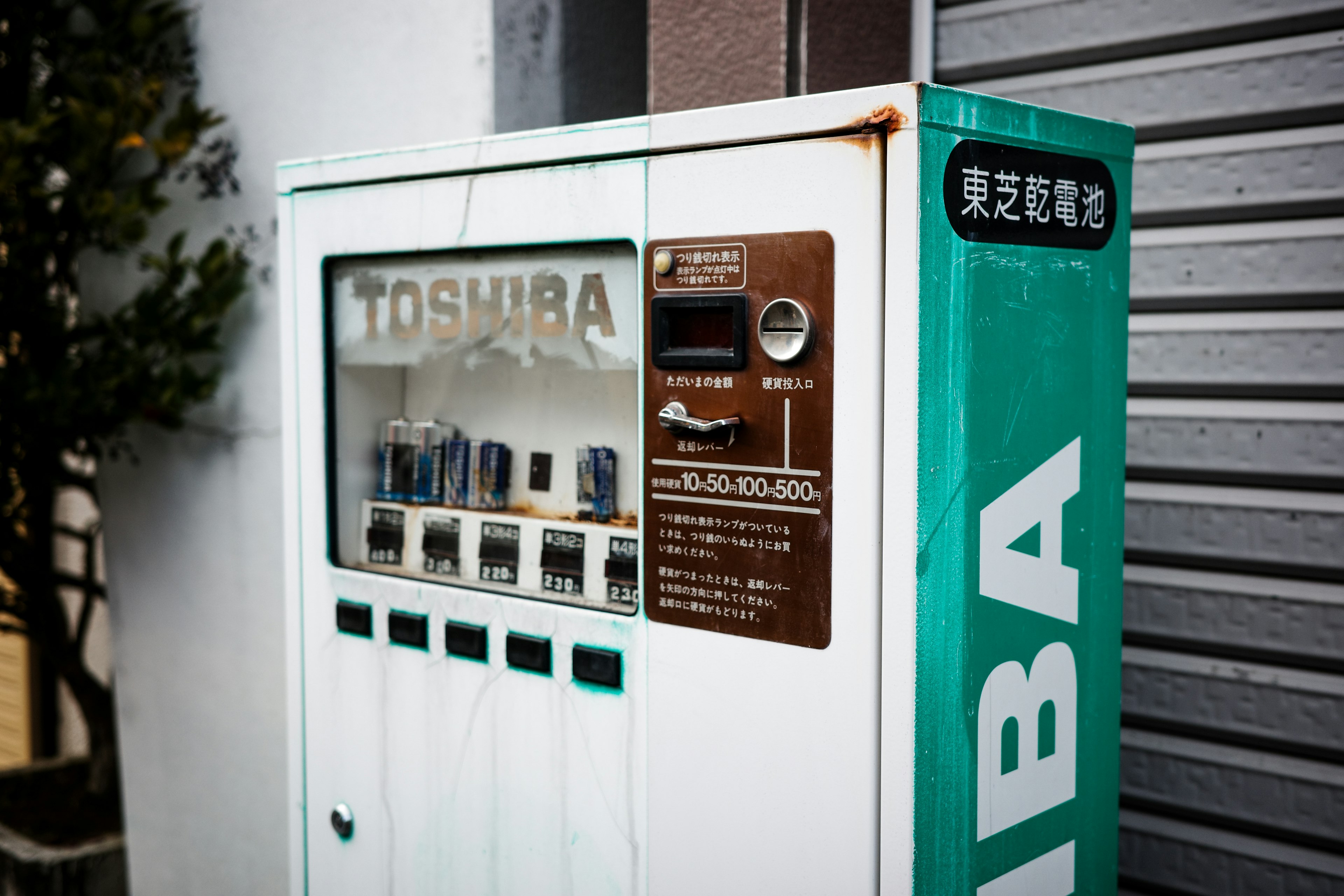 Toshiba vending machine in green and white leaning against a wall