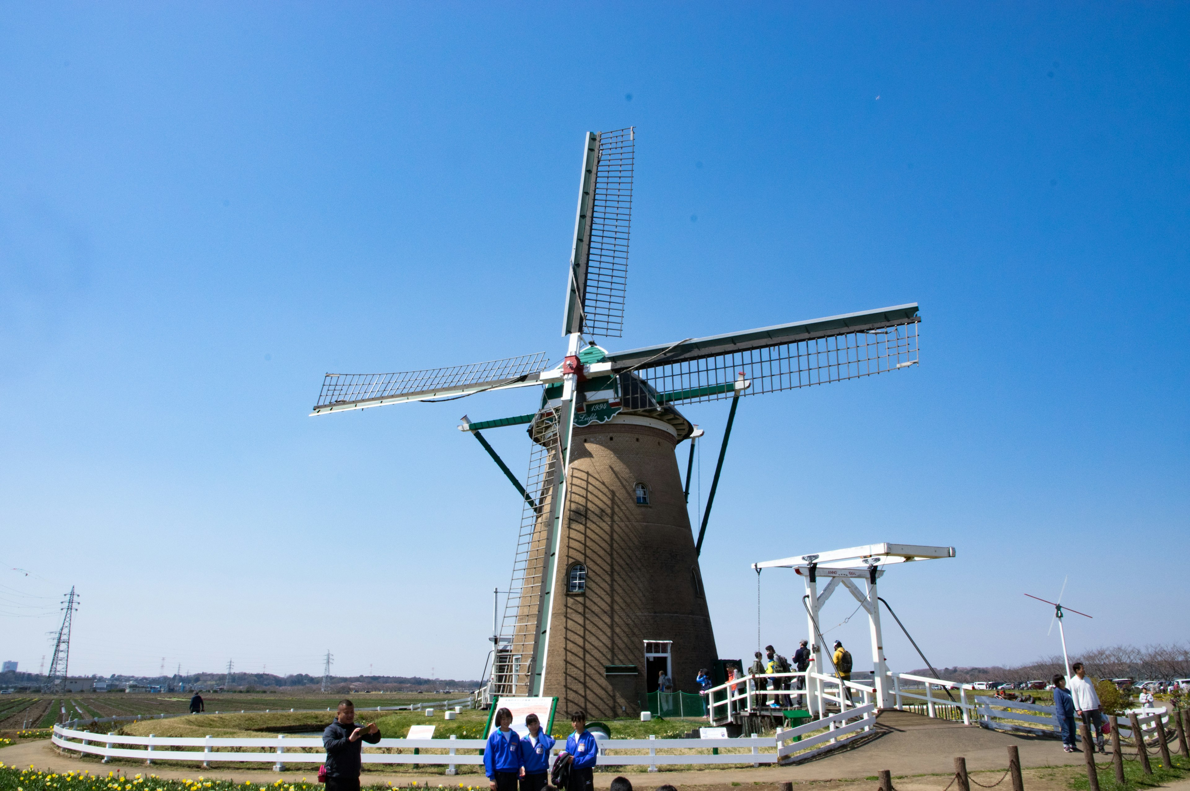 Windmill under a clear blue sky with visitors