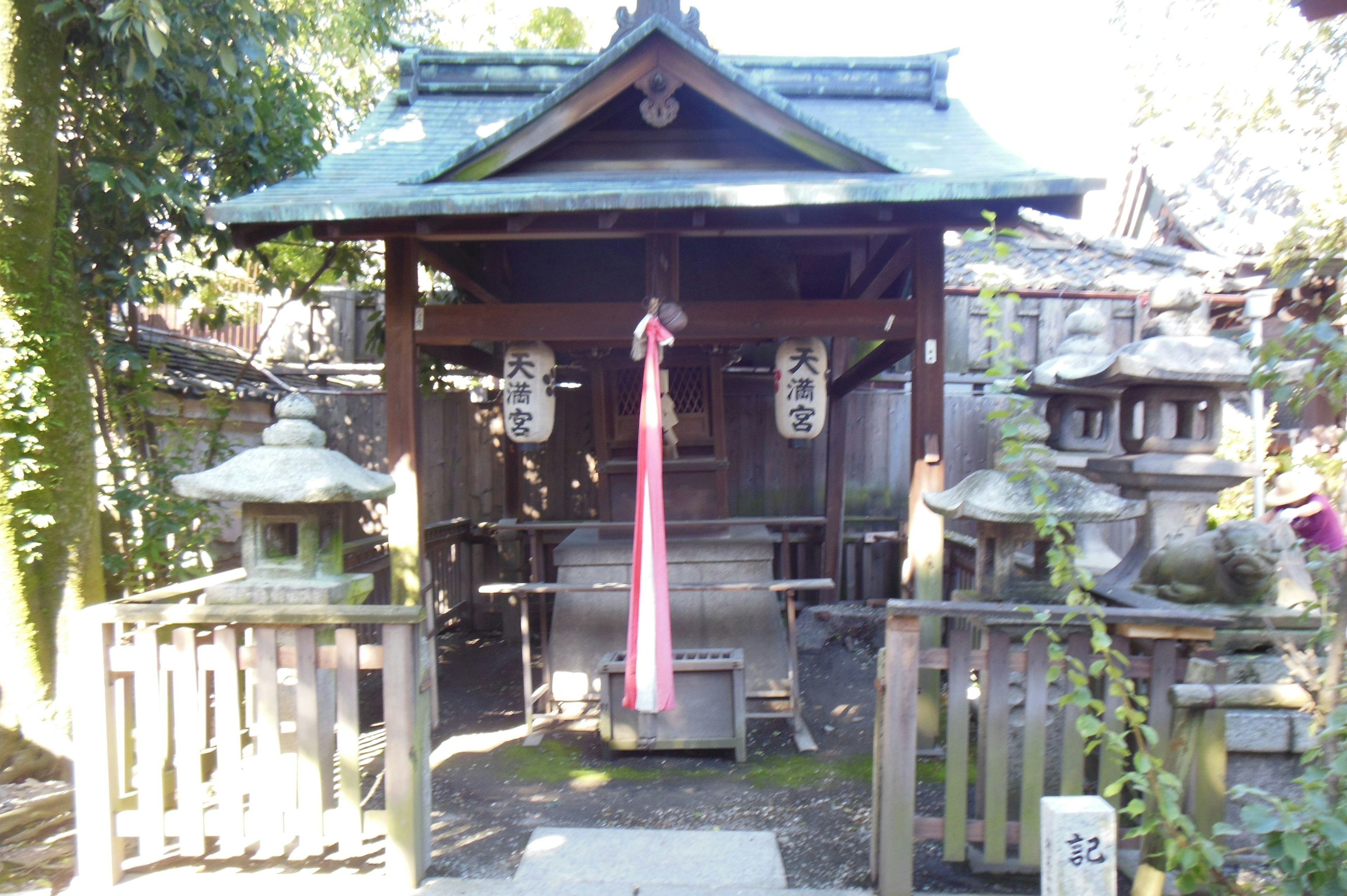 神社の小屋と周囲の石灯籠と緑の植物