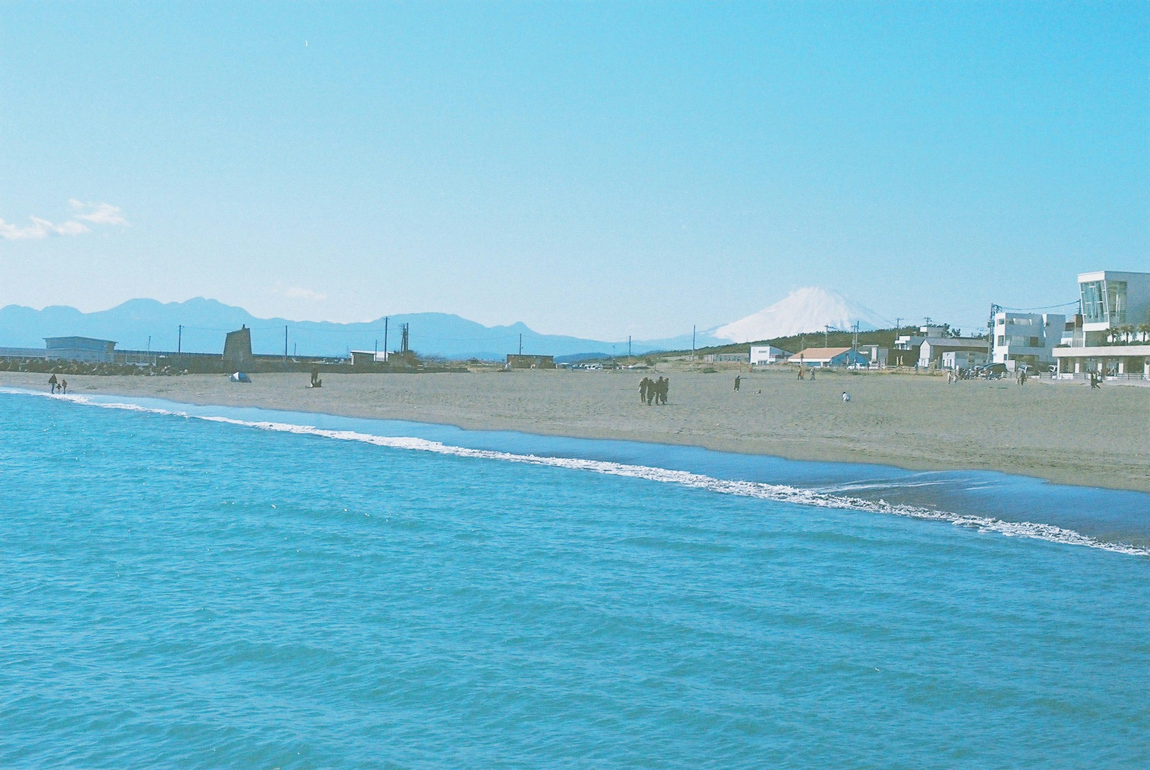 青い海と砂浜の風景に山々が背景に広がる