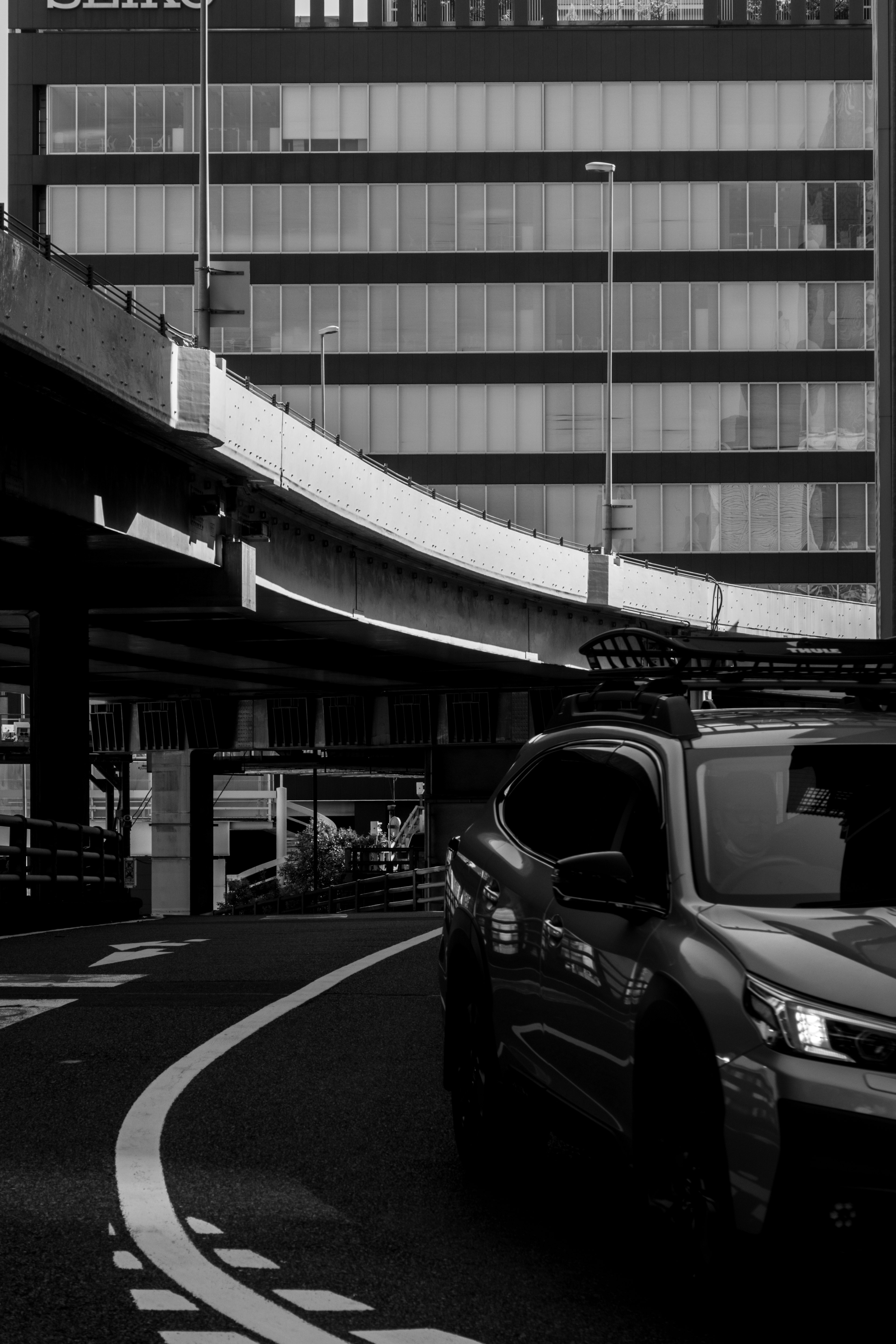 黒白の都市景観に沿った曲がりくねった道路とSUV