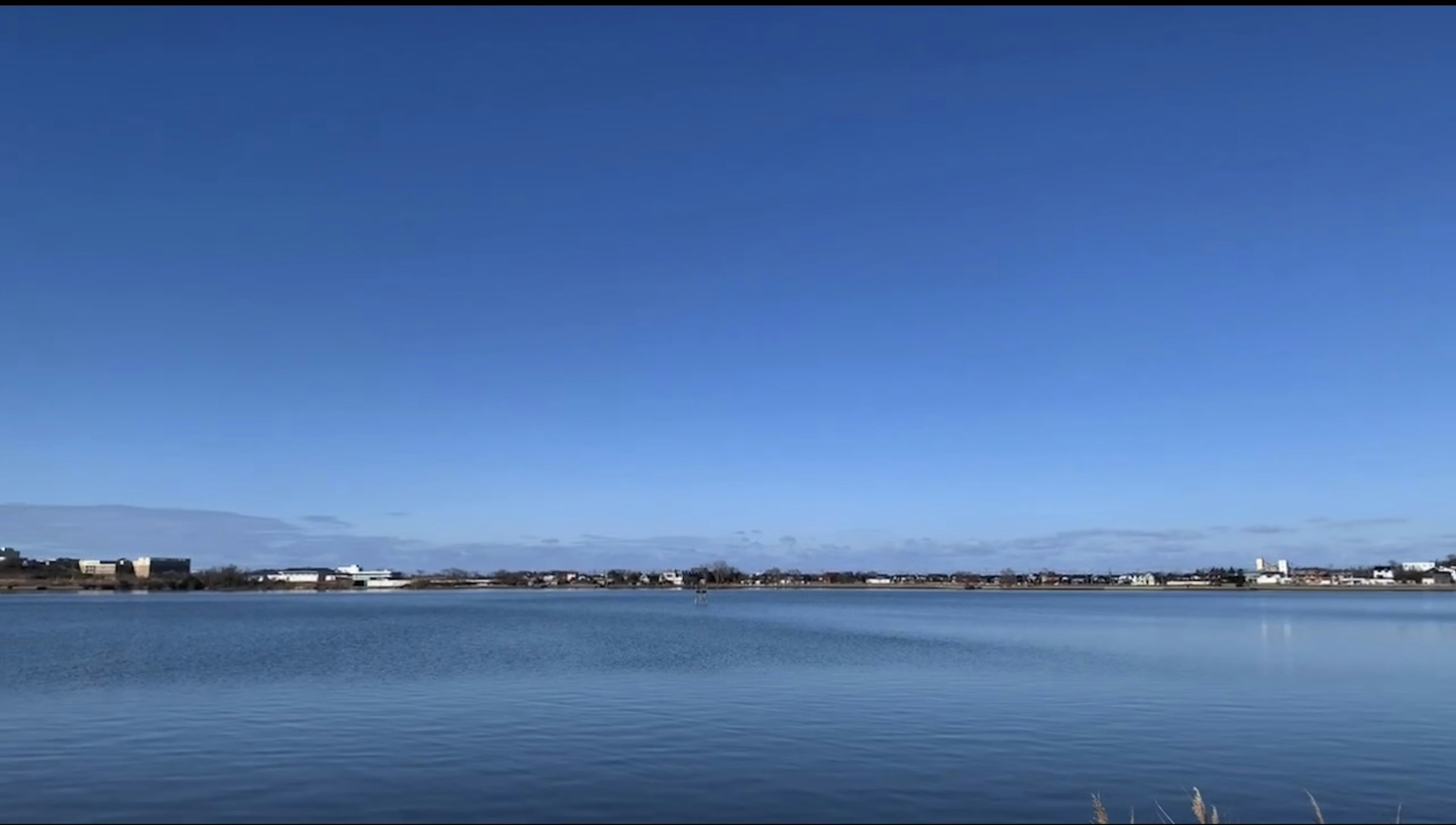 A serene landscape featuring a clear blue sky and calm water