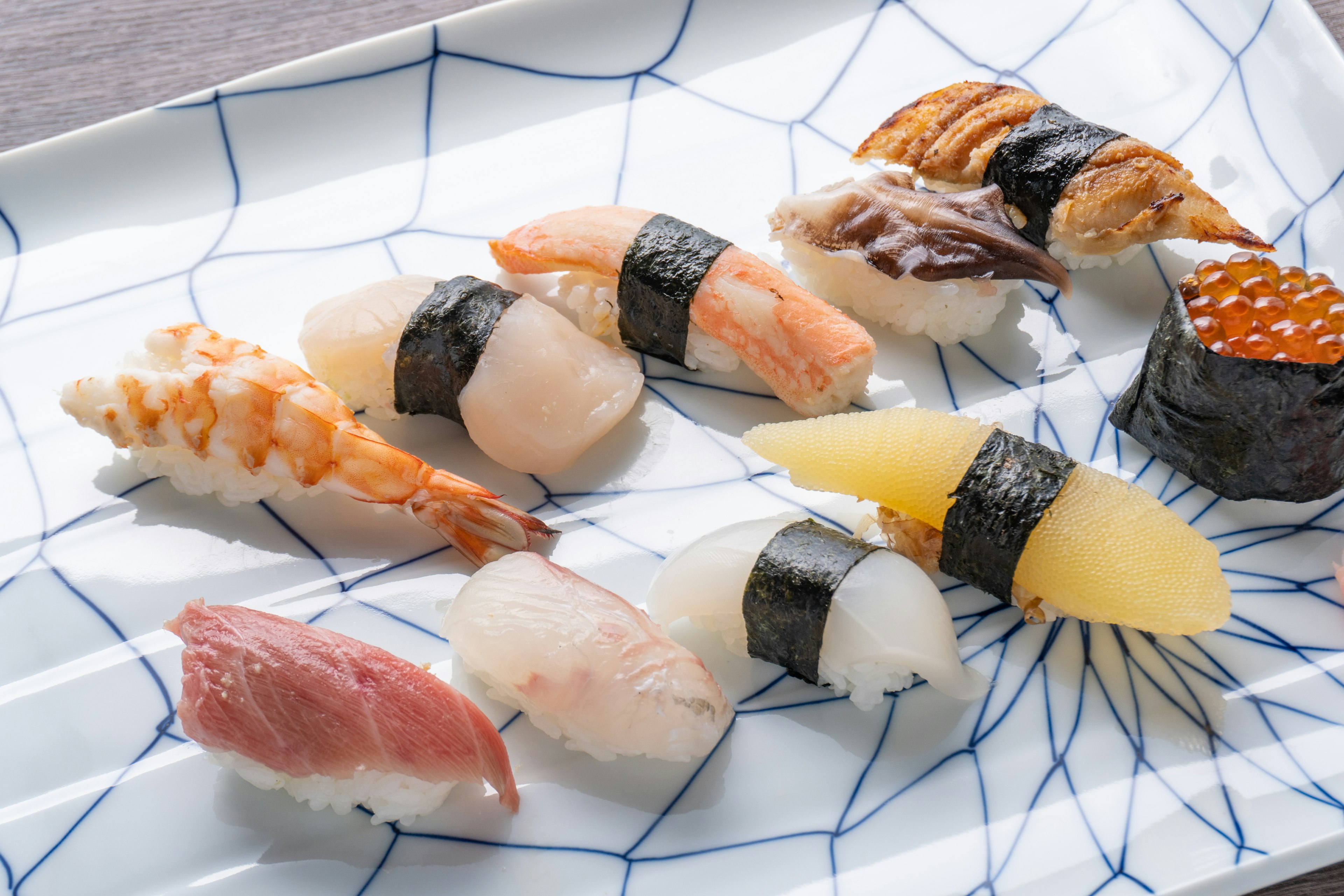 Ein Teller mit verschiedenen Sushi-Sorten, darunter Garnelen, weißer Fisch, Meeresfrüchte und Seeigel