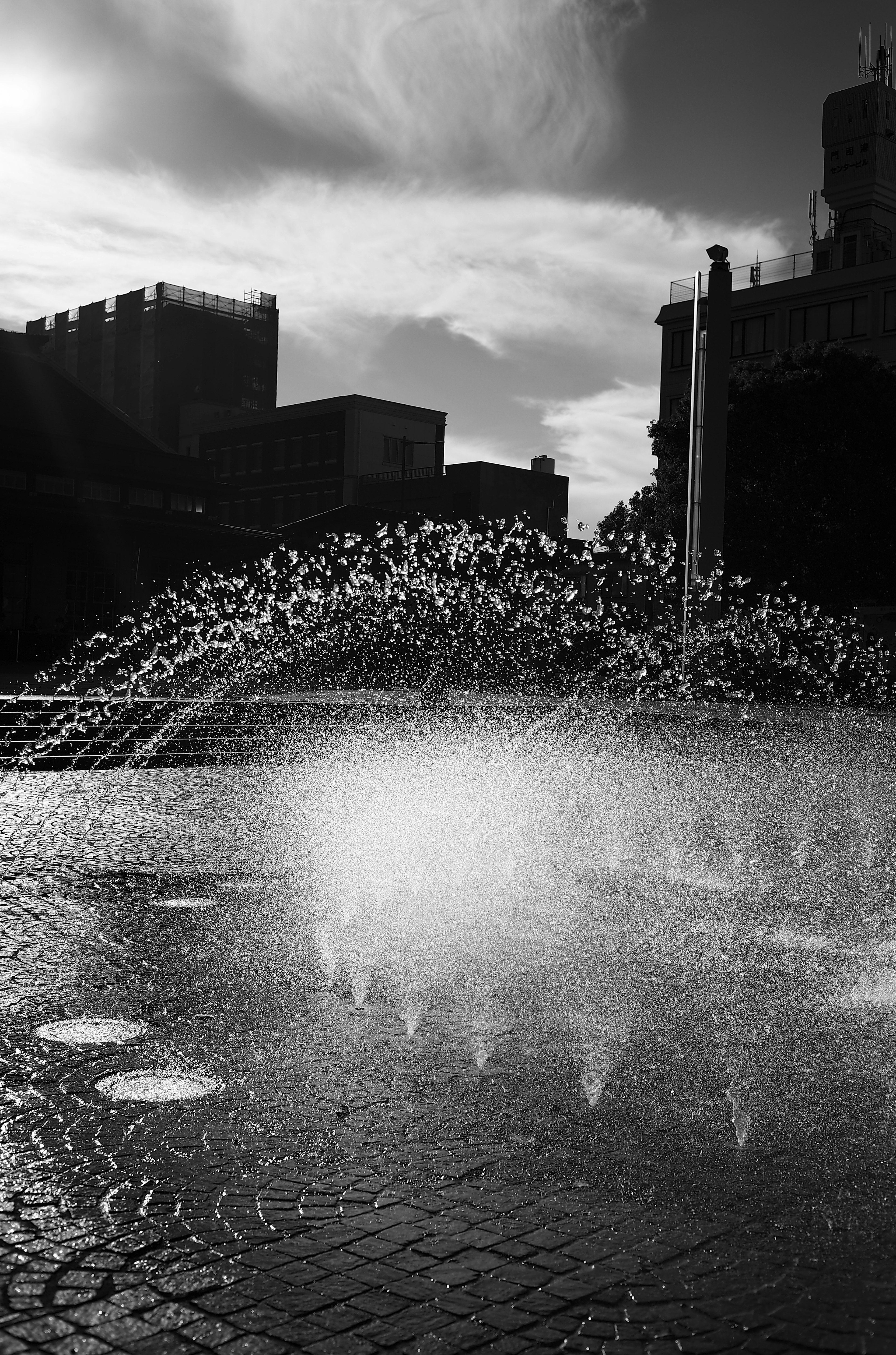 Fontana in bianco e nero con schizzi d'acqua in una piazza