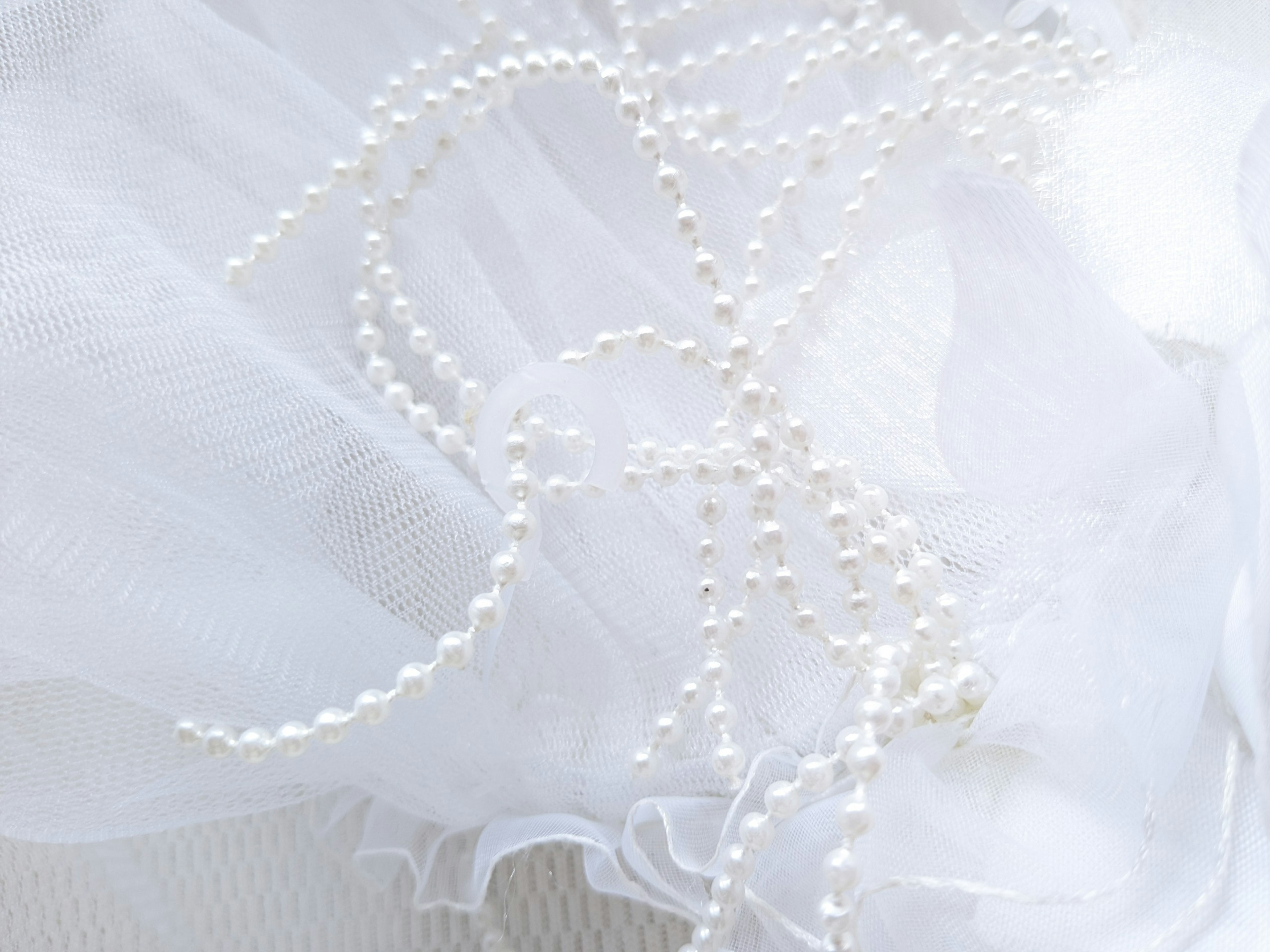 A pearl necklace scattered on a white fabric