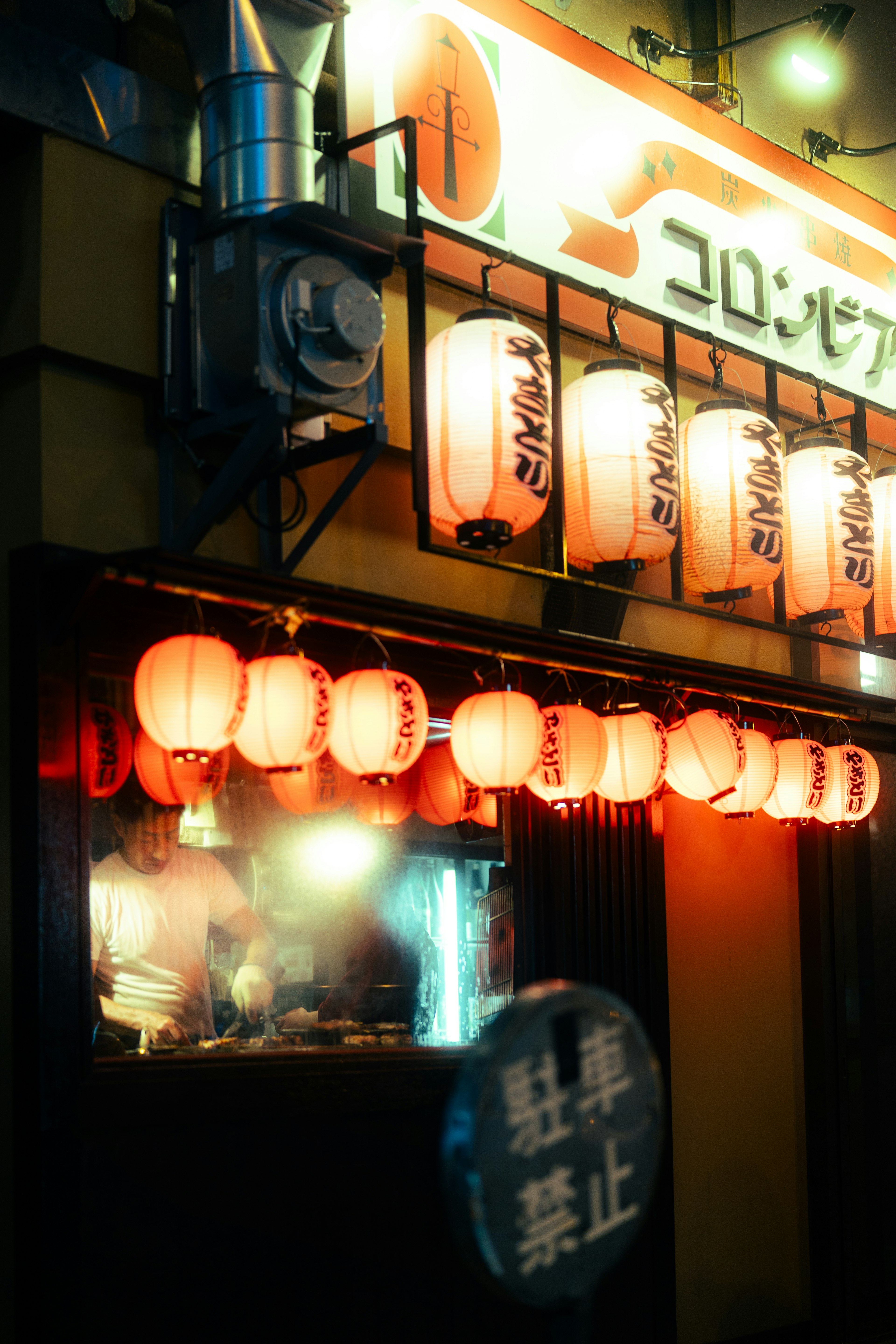 Exterior of a Japanese izakaya with red lanterns glowing at night