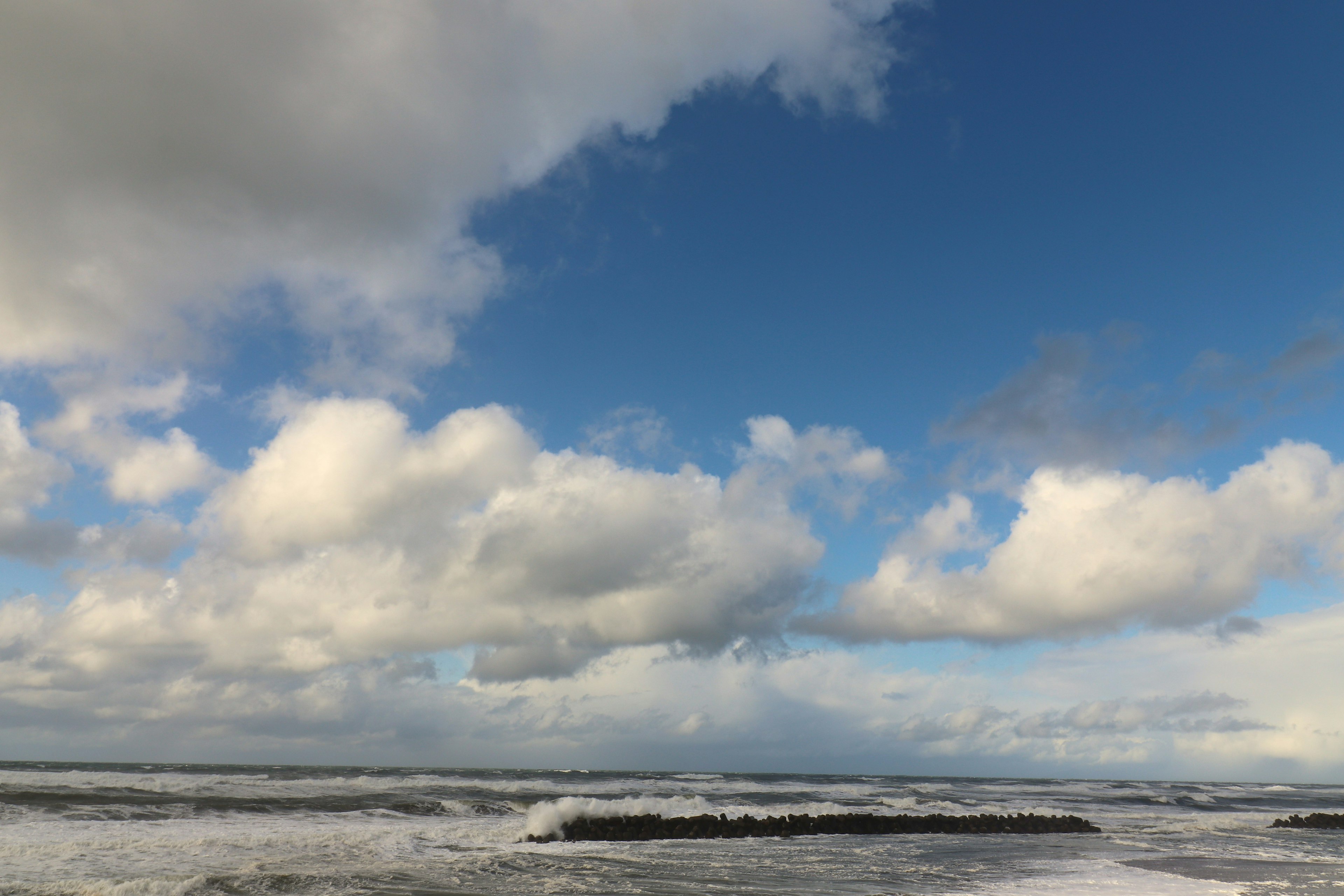 Meereslandschaft mit blauem Himmel und Wolken, Wellen brechen