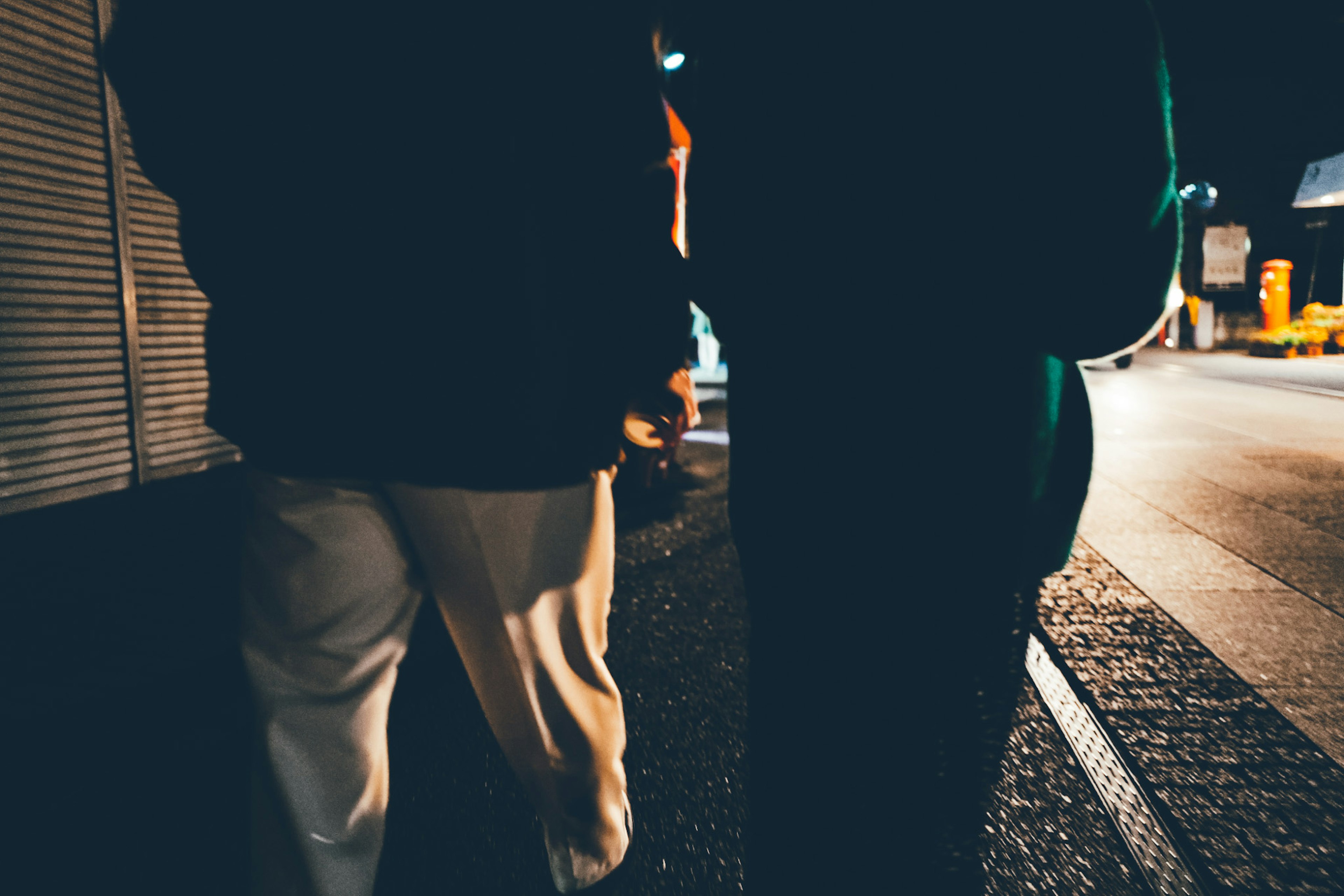 Two people walking in the night with city lights in the background