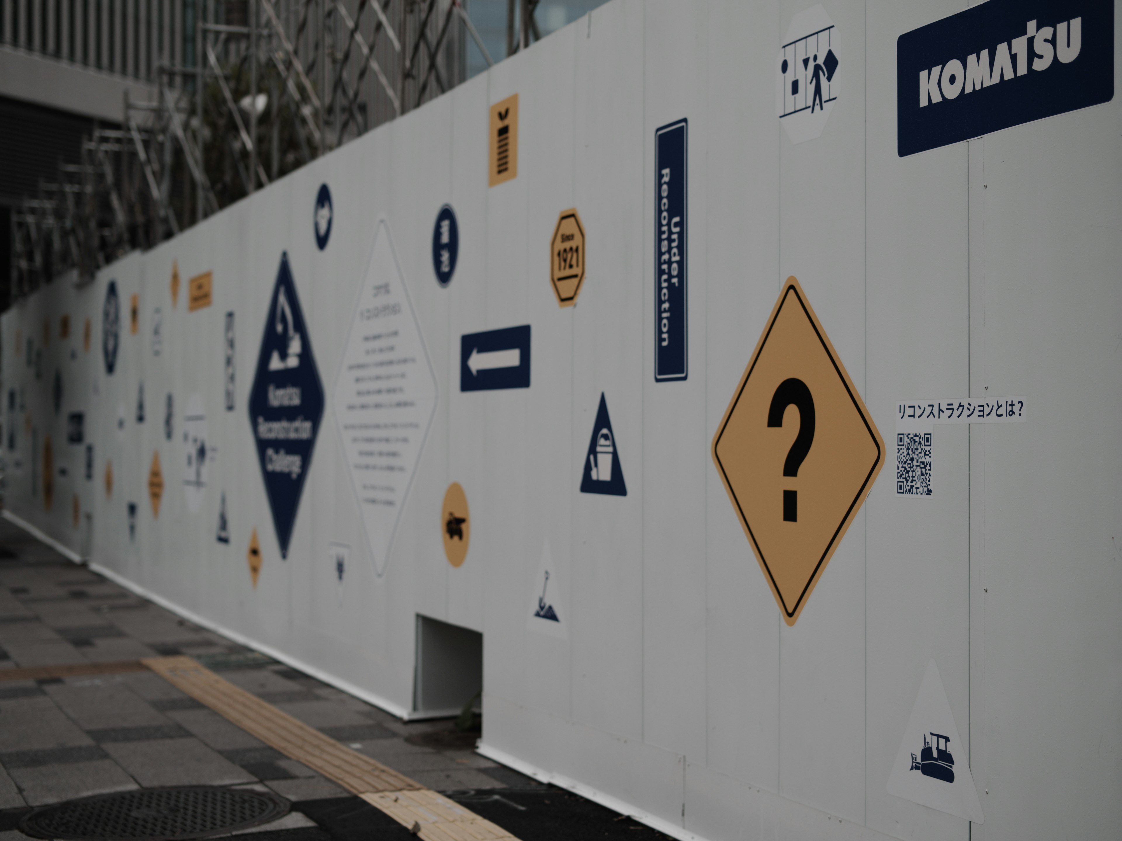 A white wall featuring various signs and logos including a question mark