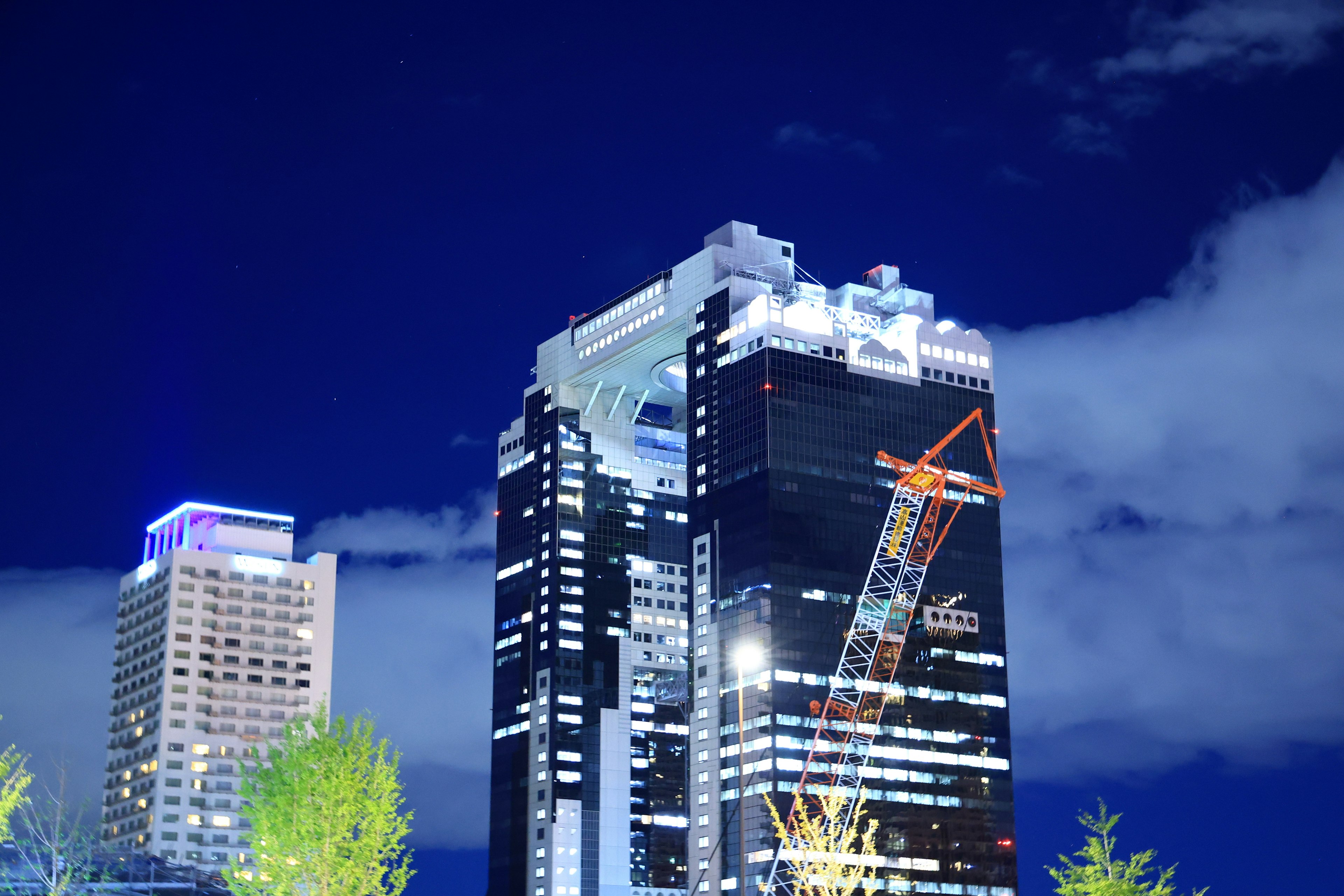 Vue nocturne d'un gratte-ciel avec grue de construction