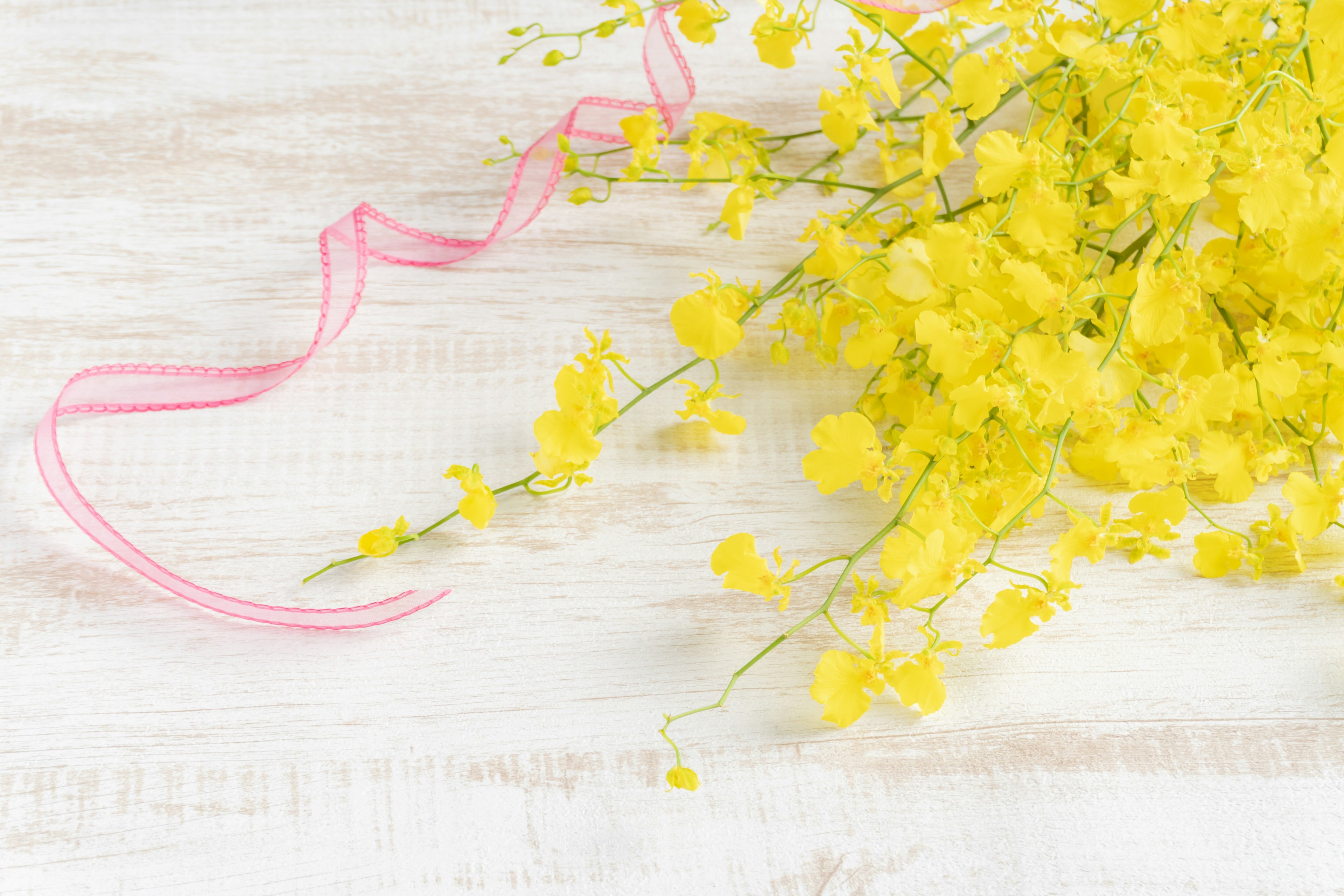 Schöne Anordnung von gelben Blumen mit einem rosa Band