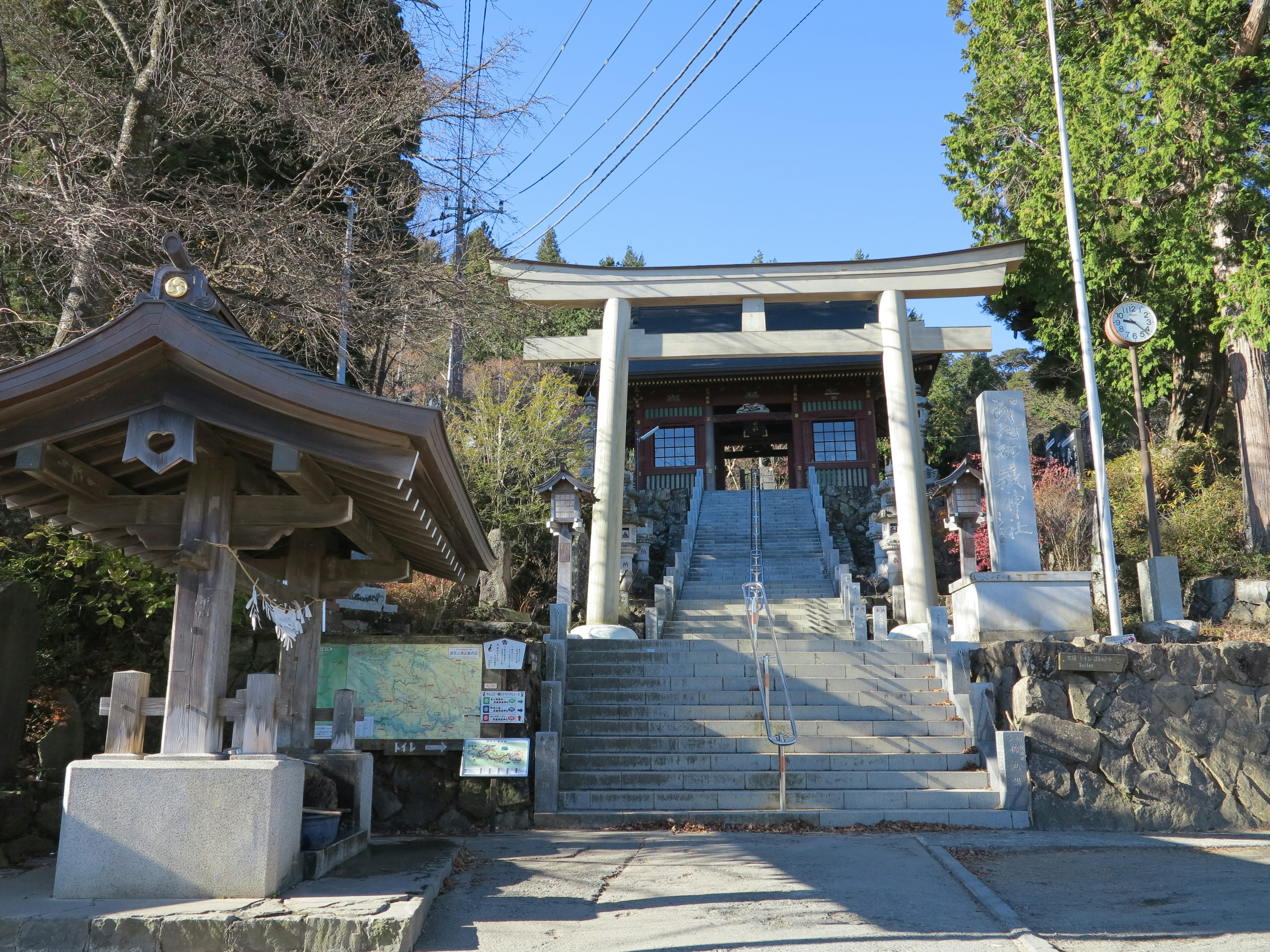 Scalinata che porta a un santuario con un torii sotto un cielo blu chiaro