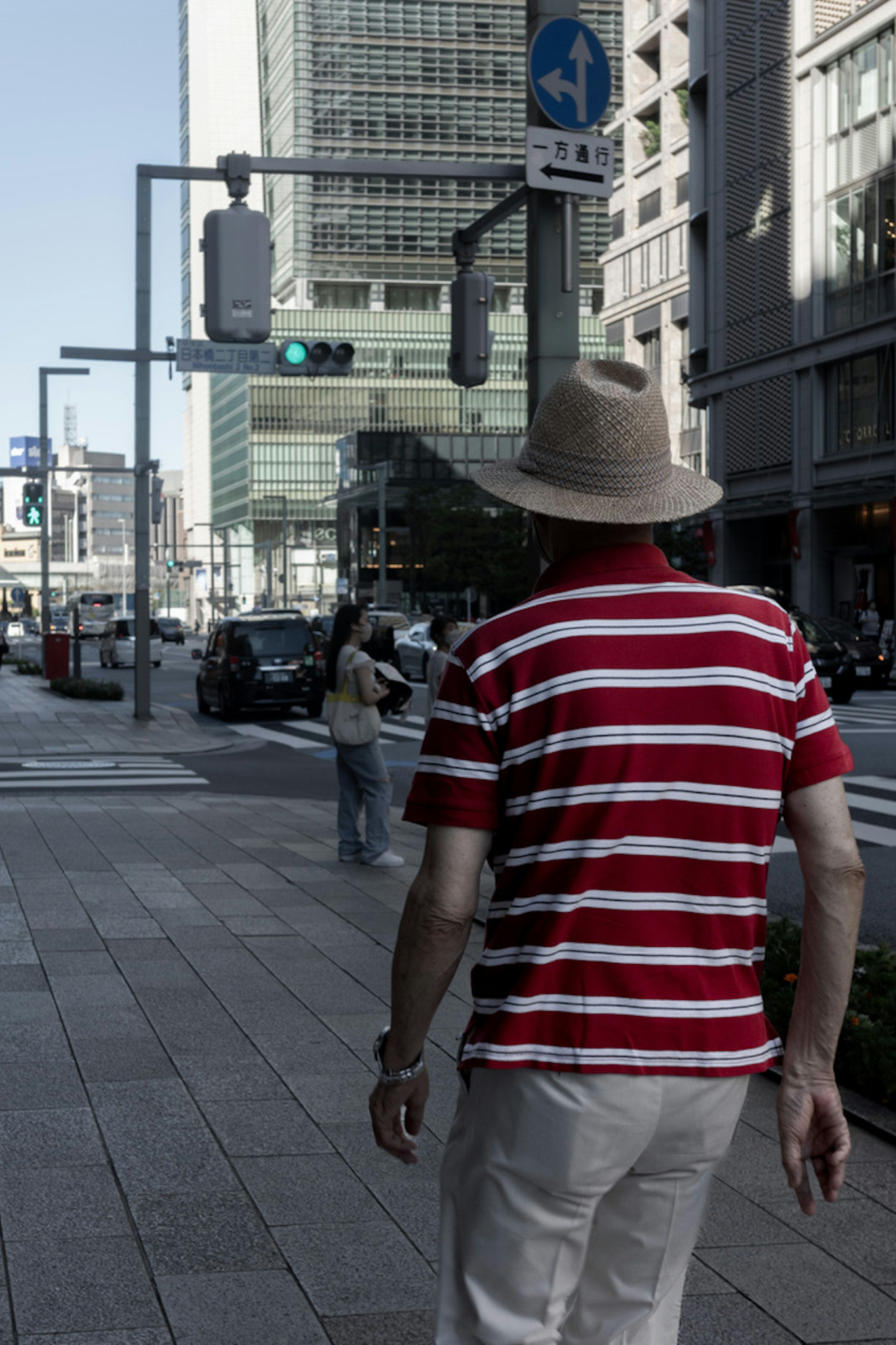 Ein Mann in einem rot-weiß gestreiften Shirt geht die Straße entlang