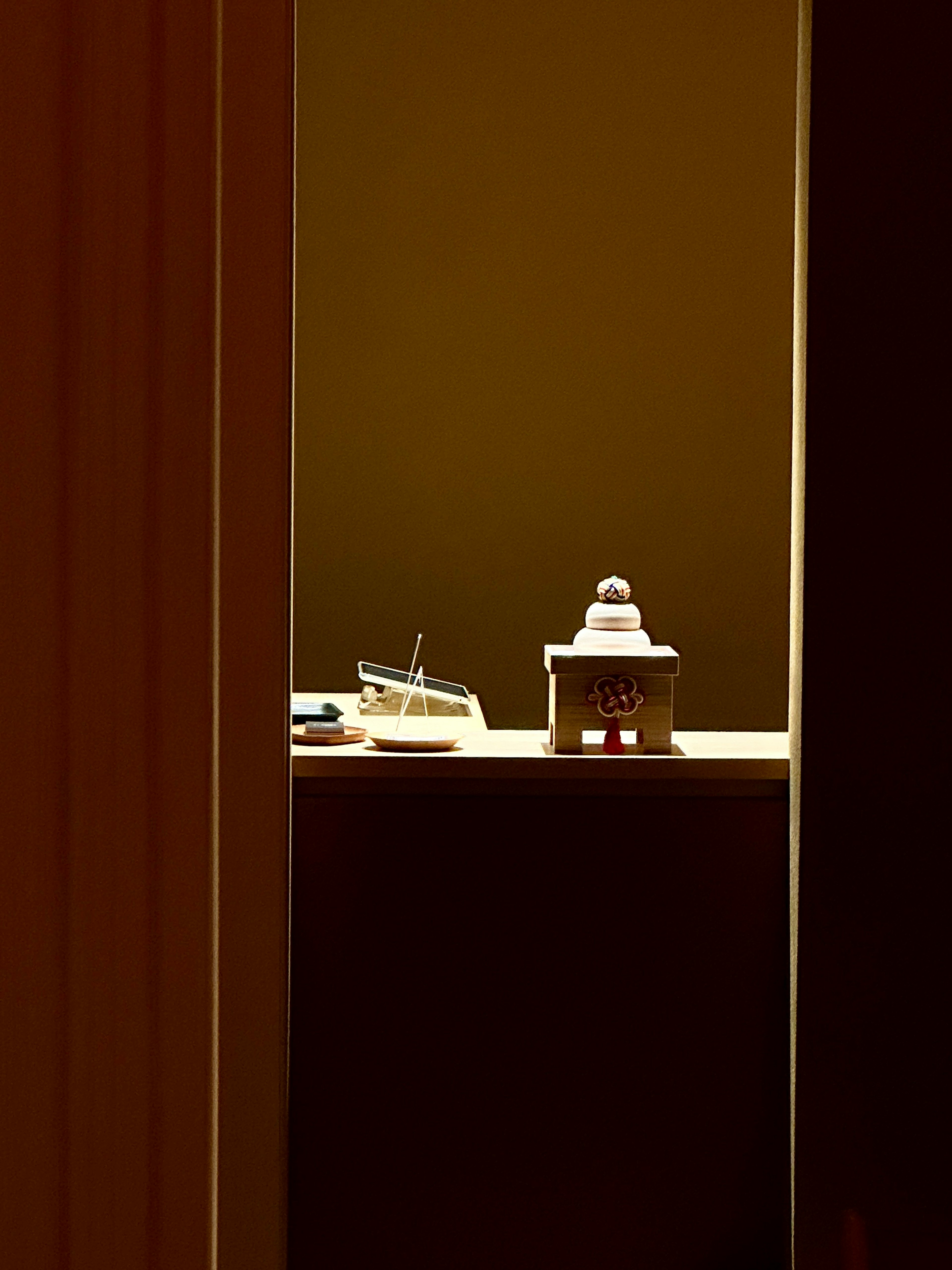 View through a door gap into a warm room featuring a white object and a small wooden house decoration