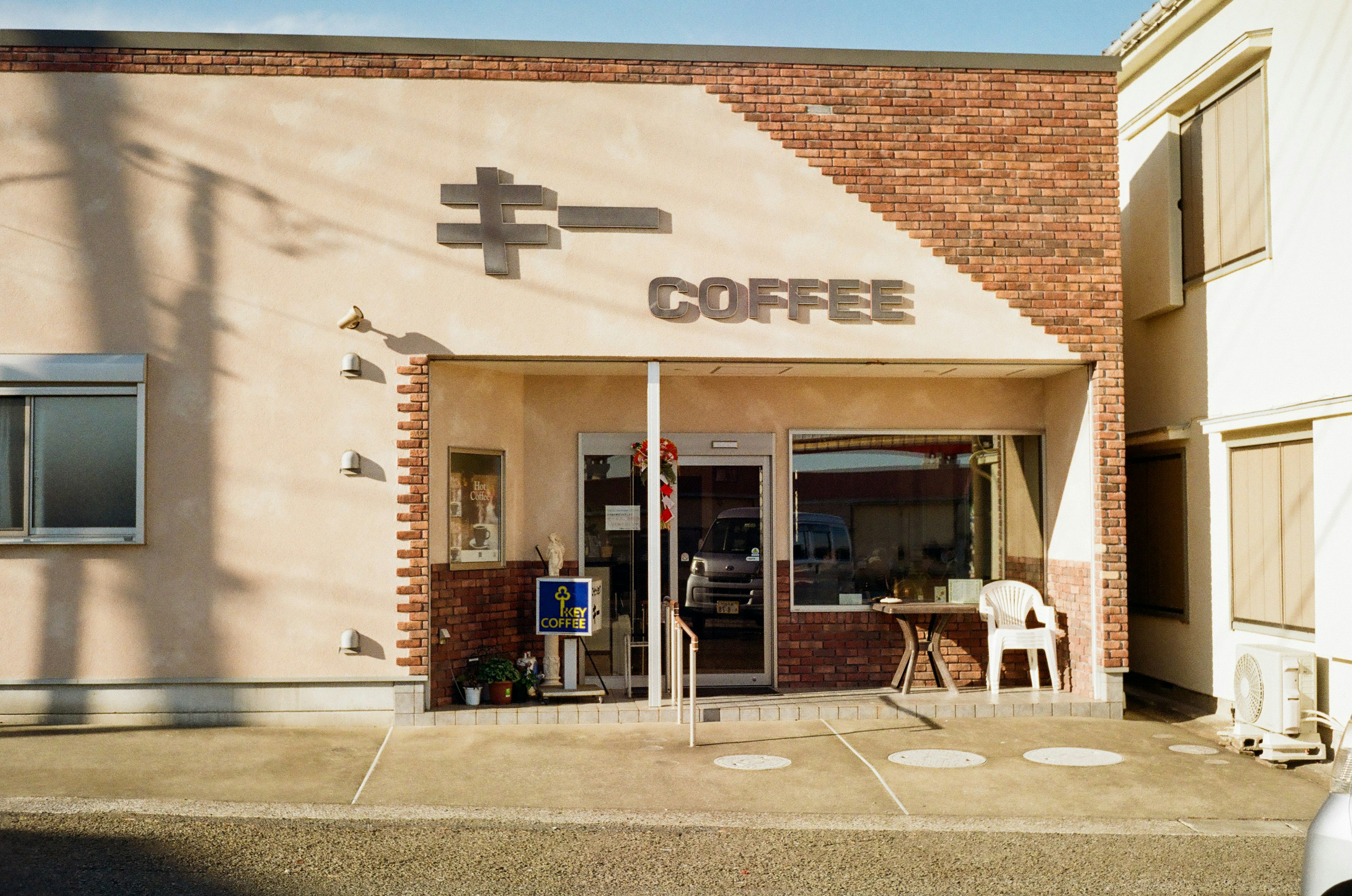 Exterior of a coffee shop featuring a brick wall and large sign