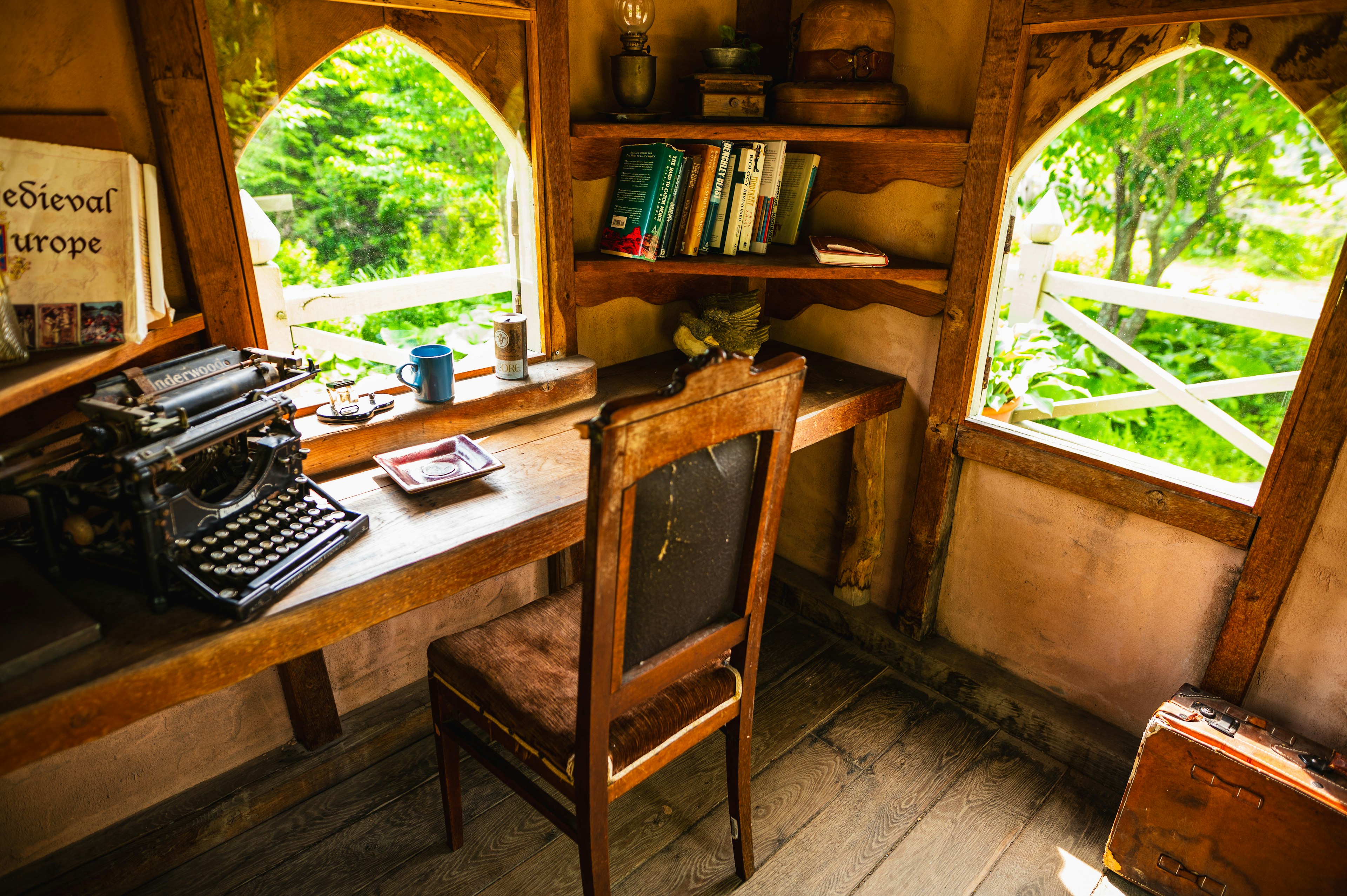 Gemütlicher Arbeitsplatz mit Holztisch und Vintage-Schreibmaschine mit Blick ins Grüne