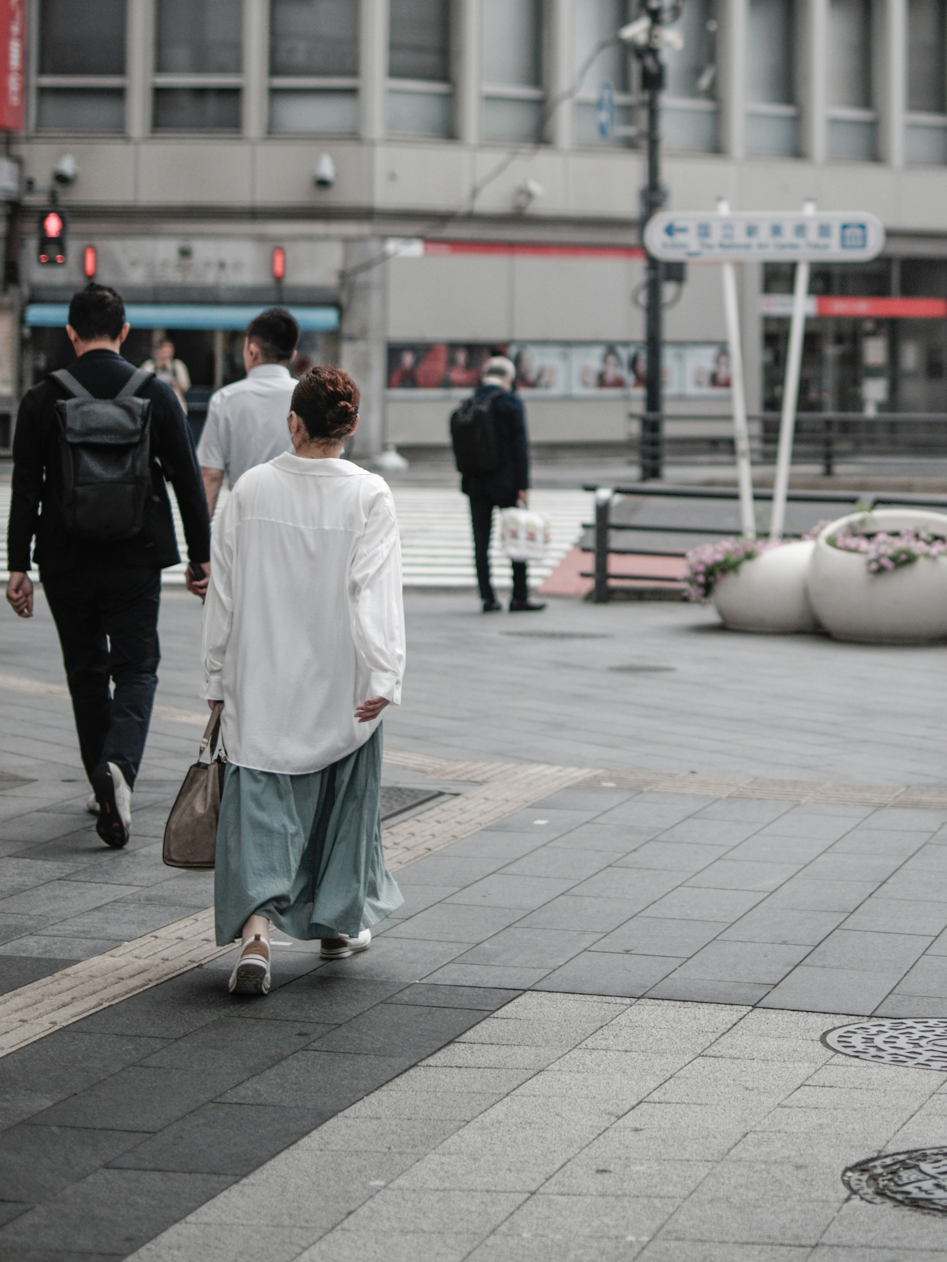 사람들이 거리에서 걷고 있는 도시 풍경 흰 셔츠와 파란 치마를 입은 여자가 뒤로 걷고 있다