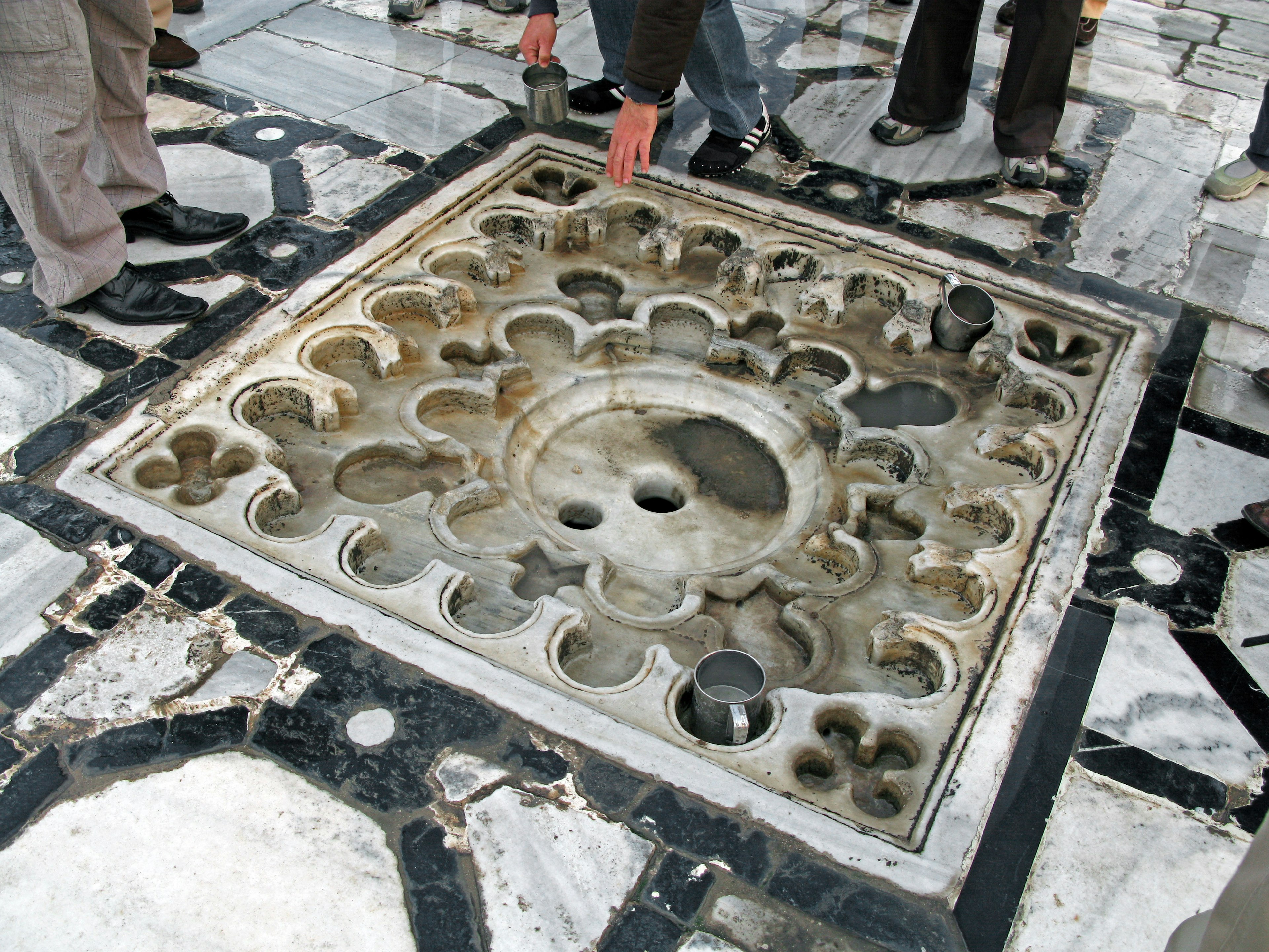 Decorative stone panel on marble floor with people touching it