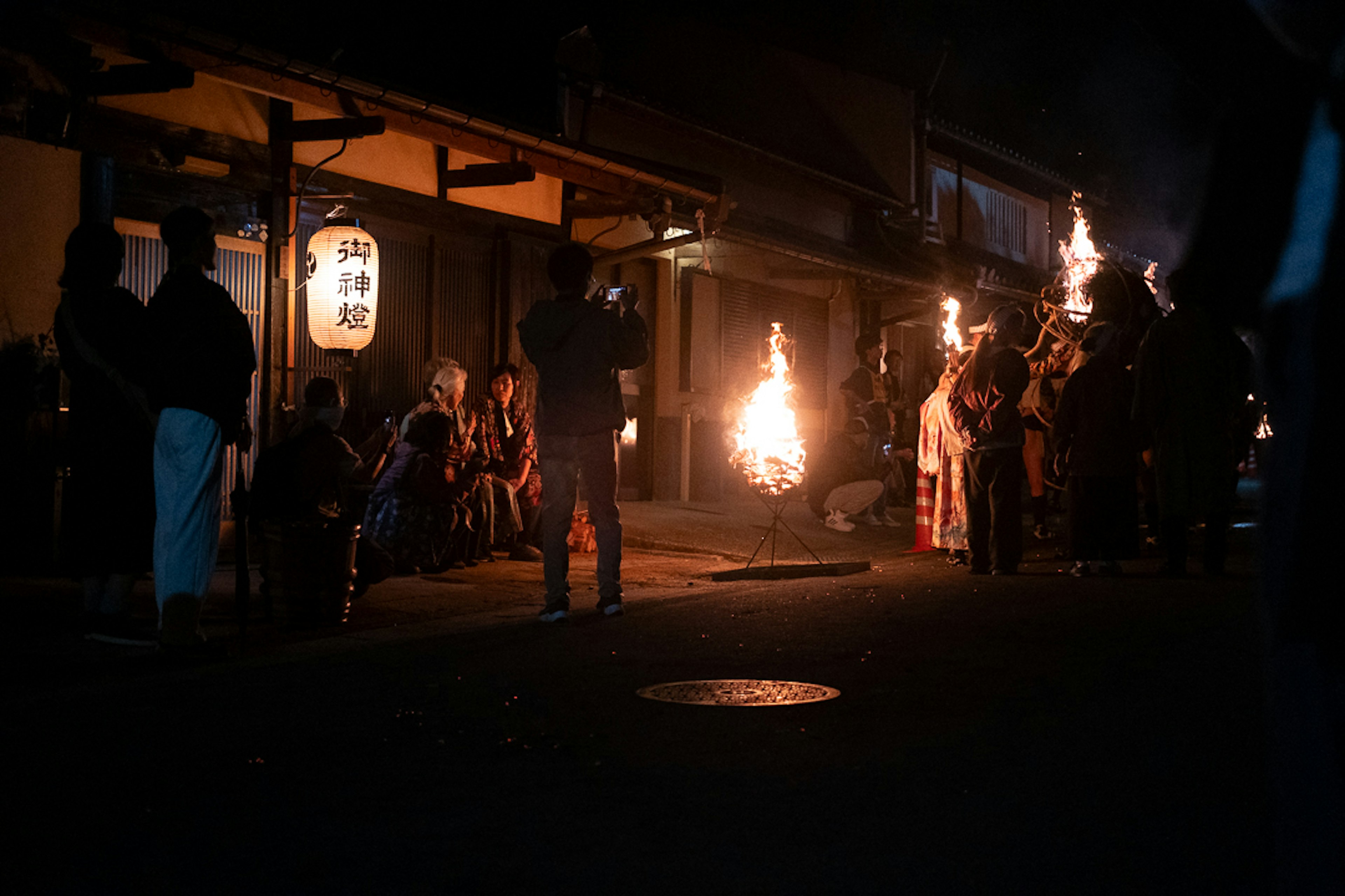 Escena de festival nocturno con personas sosteniendo antorchas