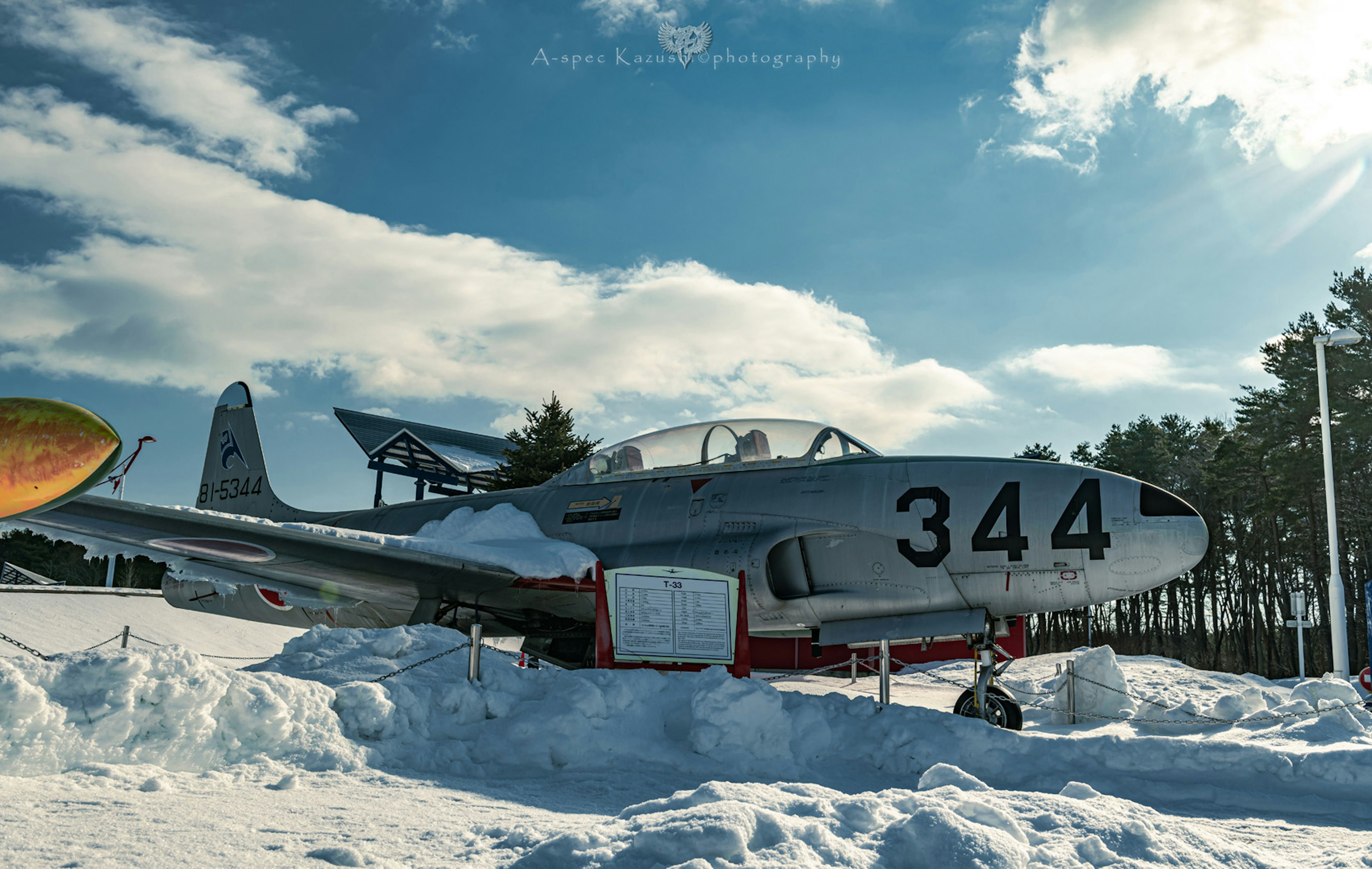 雪に覆われた航空機344号が青空の下に展示されている