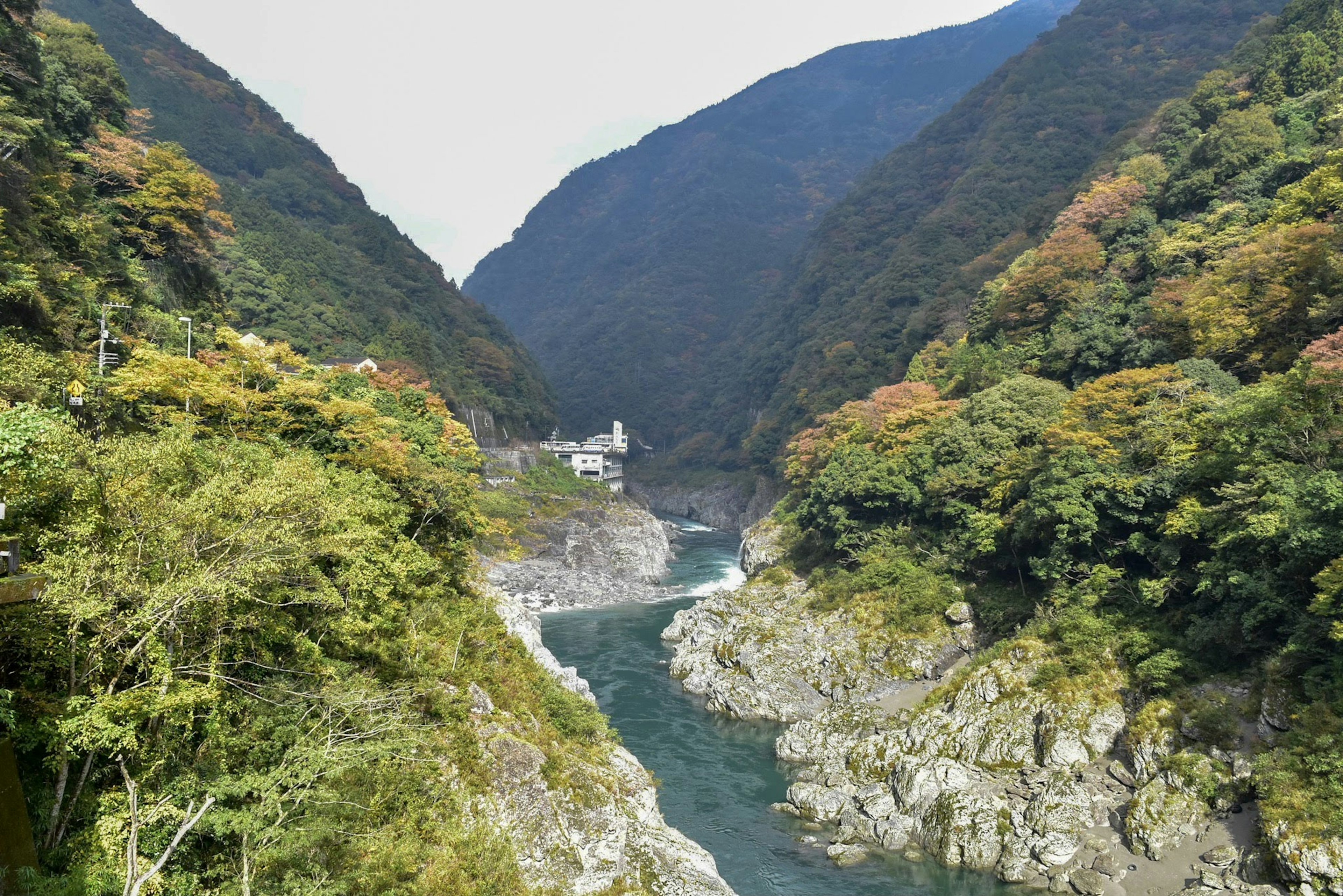 Scenic view of a gorge with a river surrounded by mountains and autumn foliage