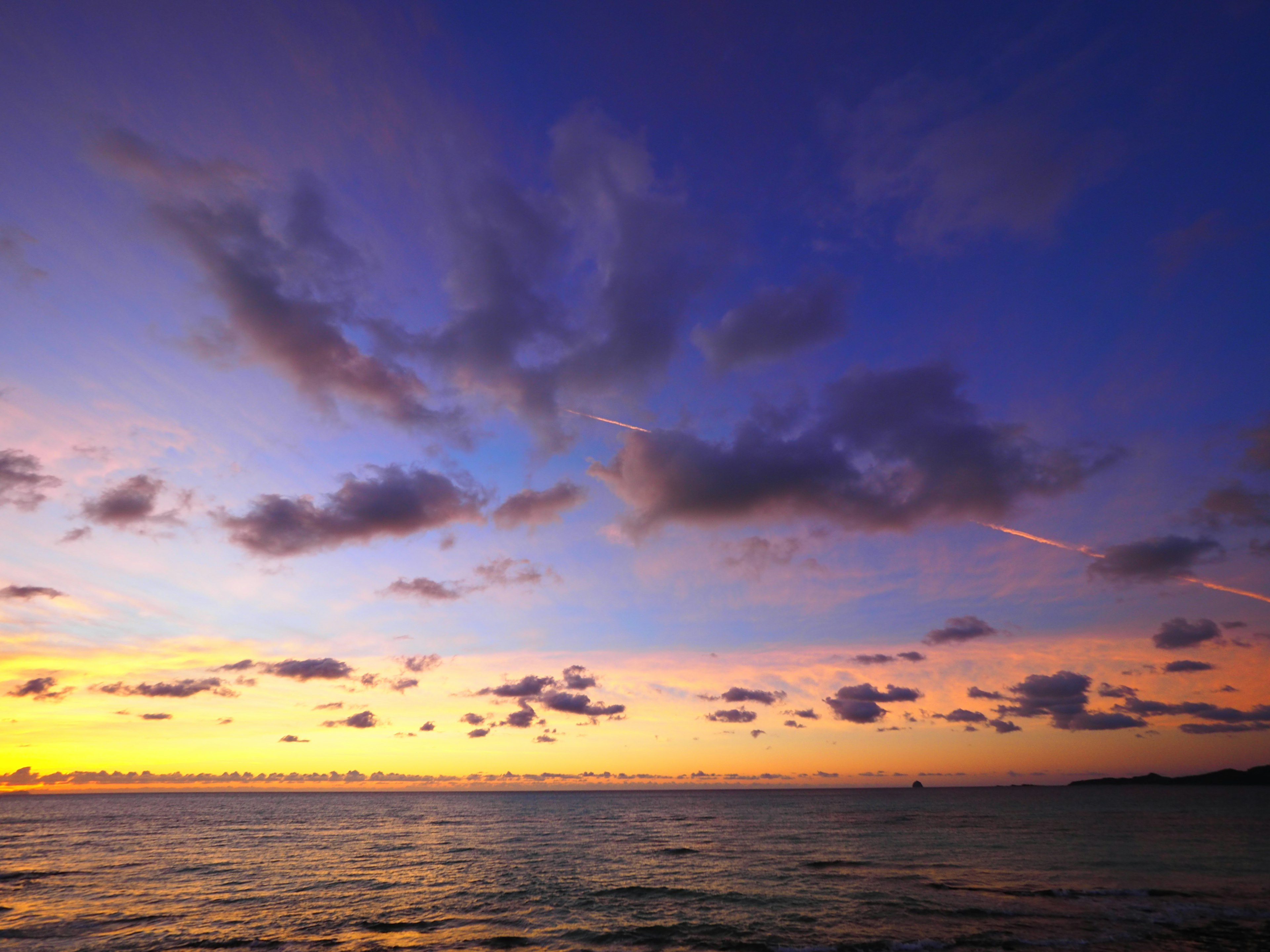 Schöner Sonnenuntergangshimmel über dem Ozean mit orange und lila Farbtönen und verstreuten Wolken