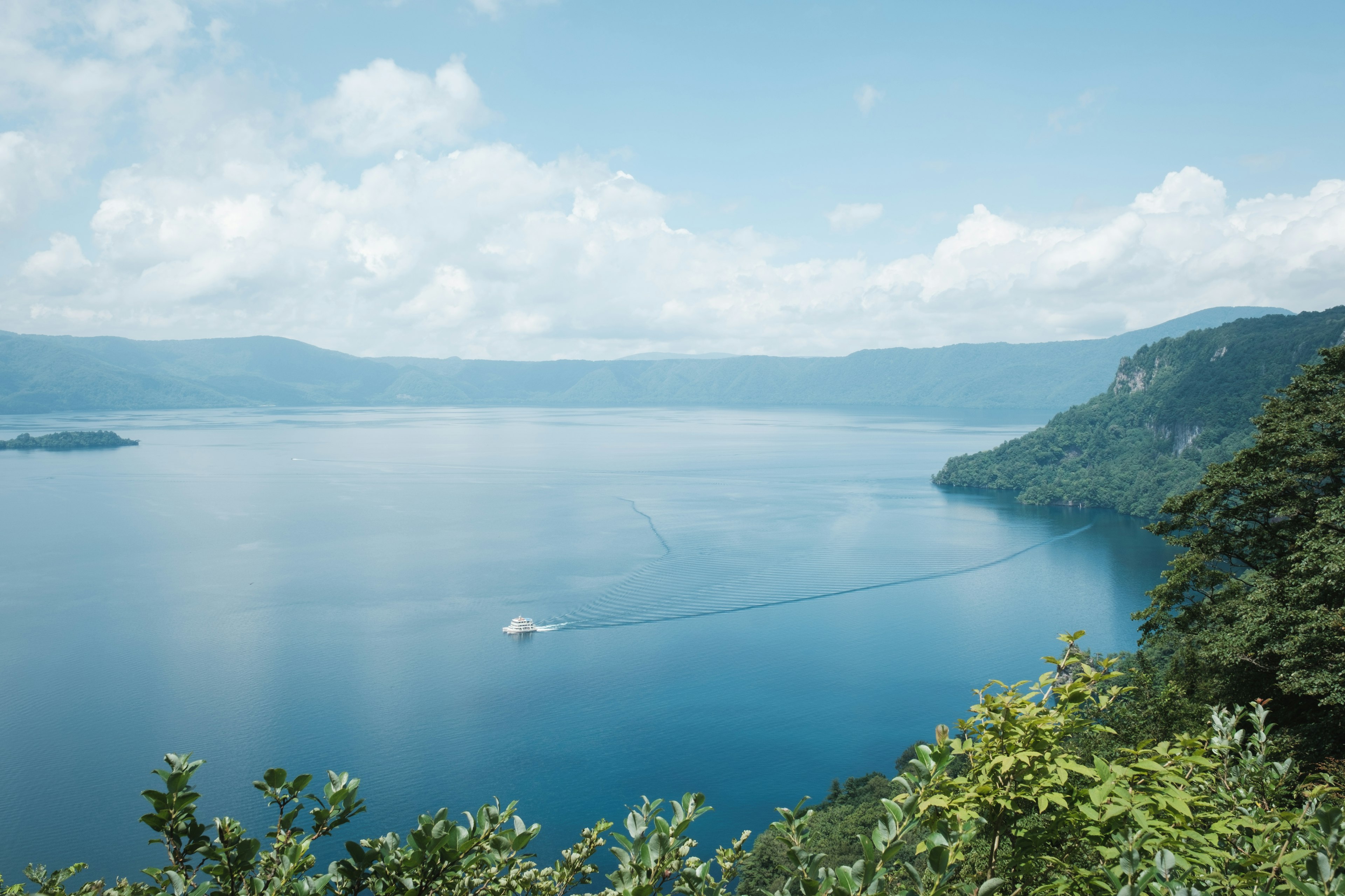 Un lago blu sereno circondato da colline verdi e montagne lontane