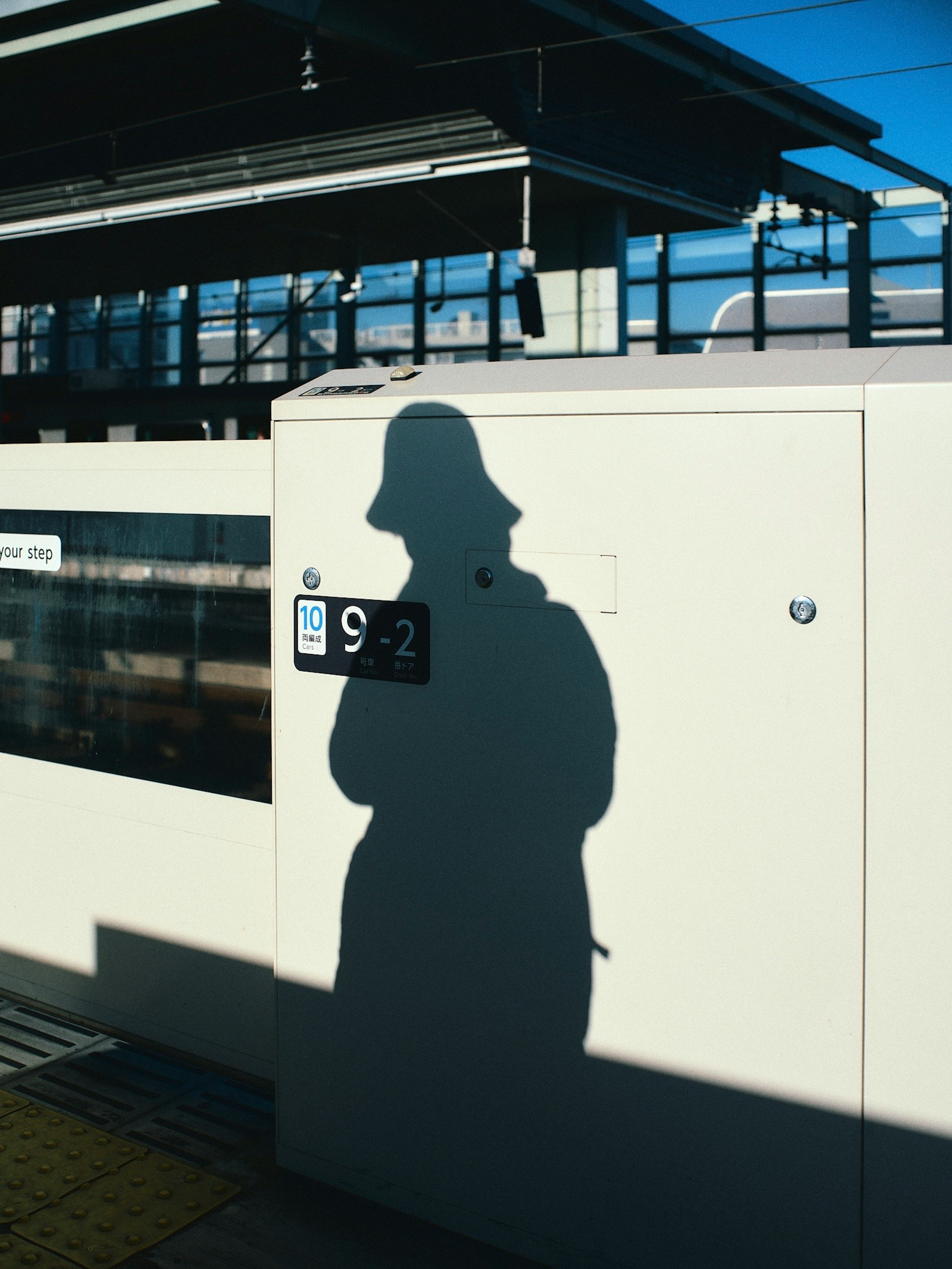 Ombre d'une personne sur une structure de gare avec ciel bleu