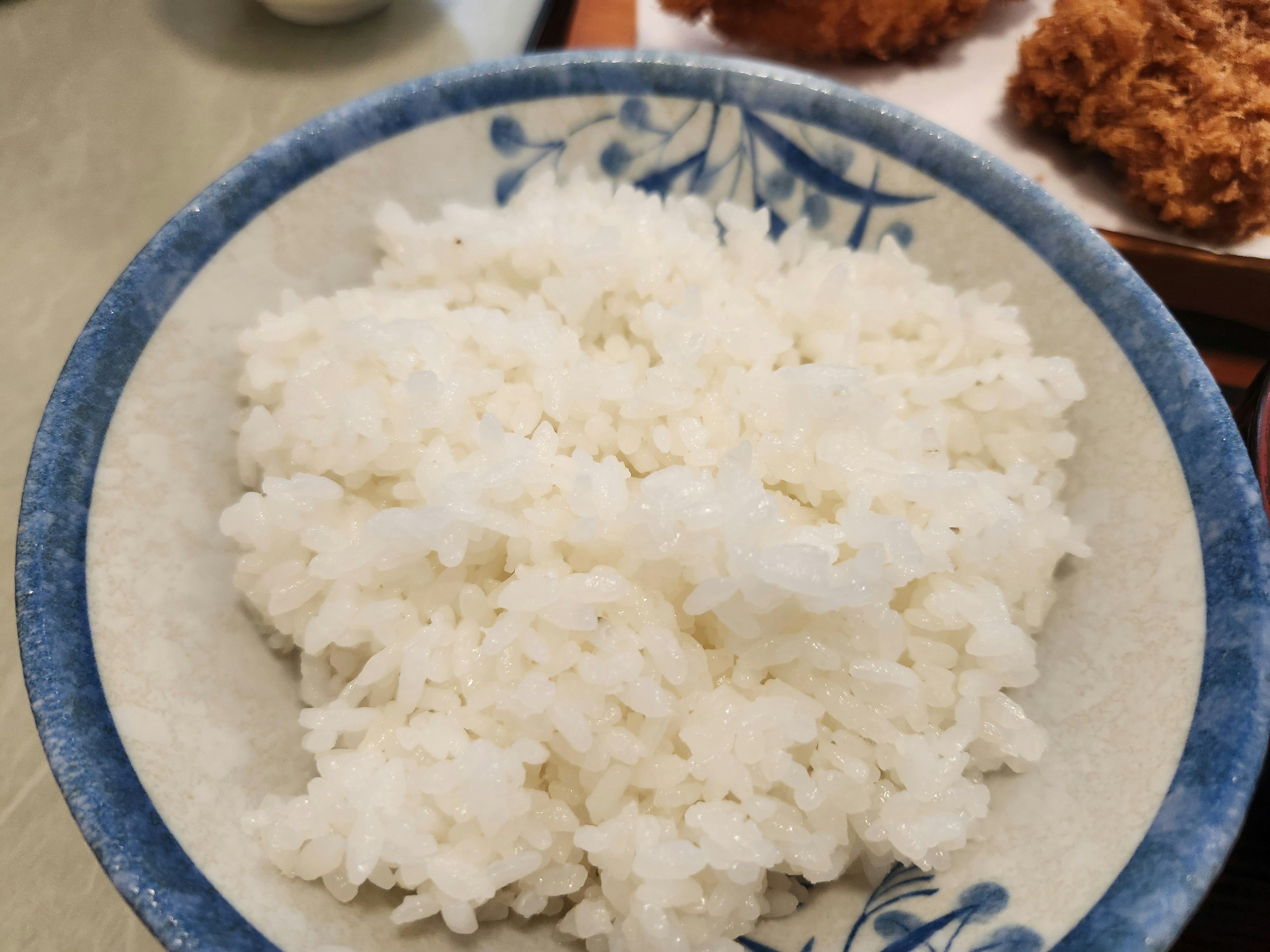 A bowl of fluffy white rice served in a blue rimmed dish