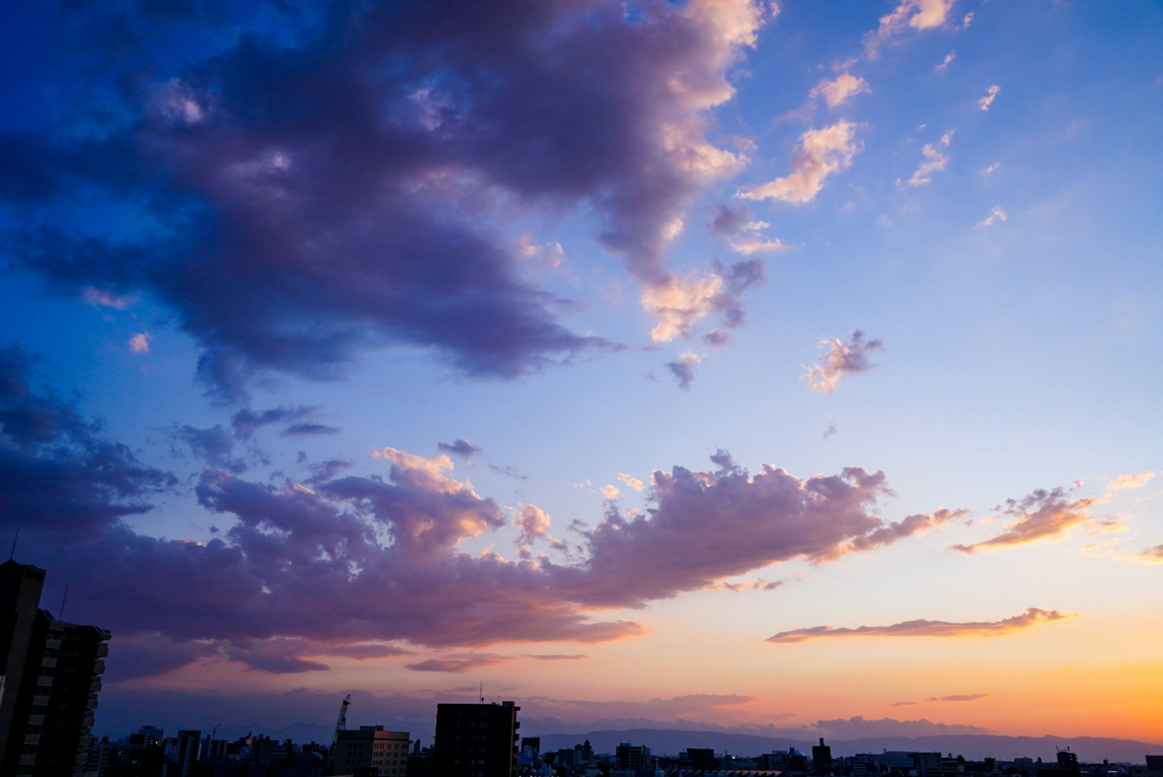 Schöner Sonnenuntergangshimmel mit Wolken und Stadtsilhouette