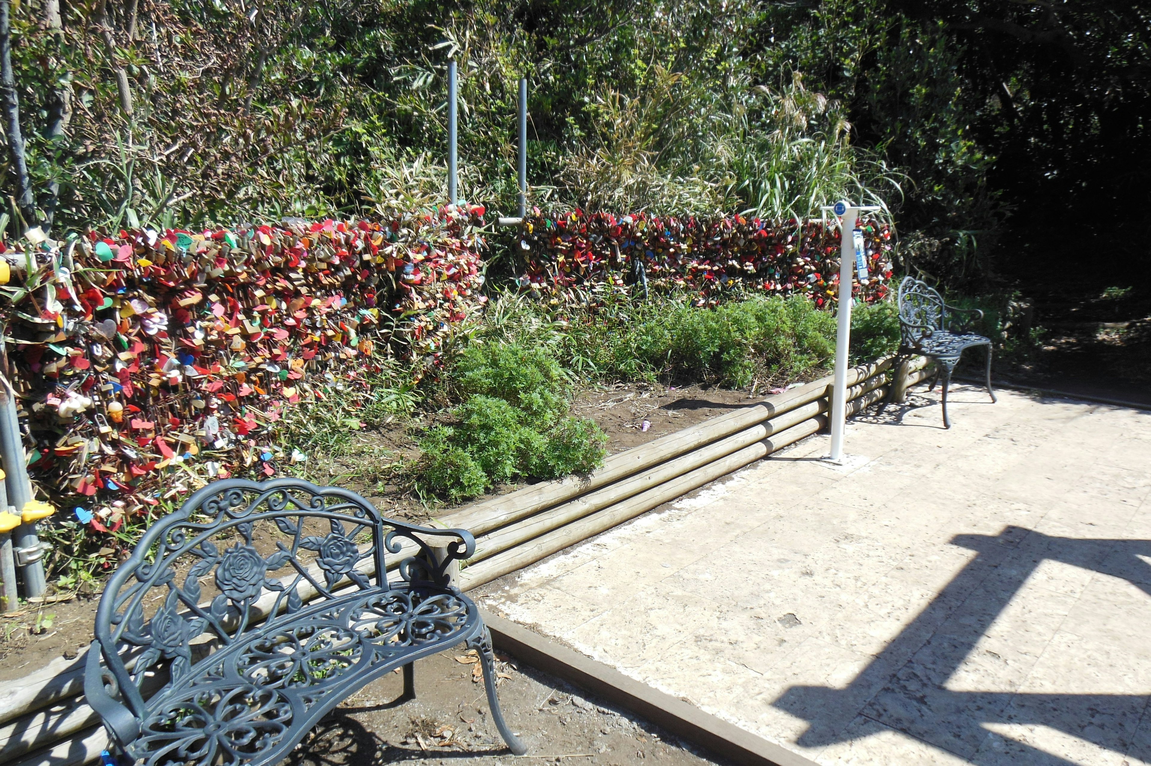 A quiet garden corner featuring a colorful lock-covered fence