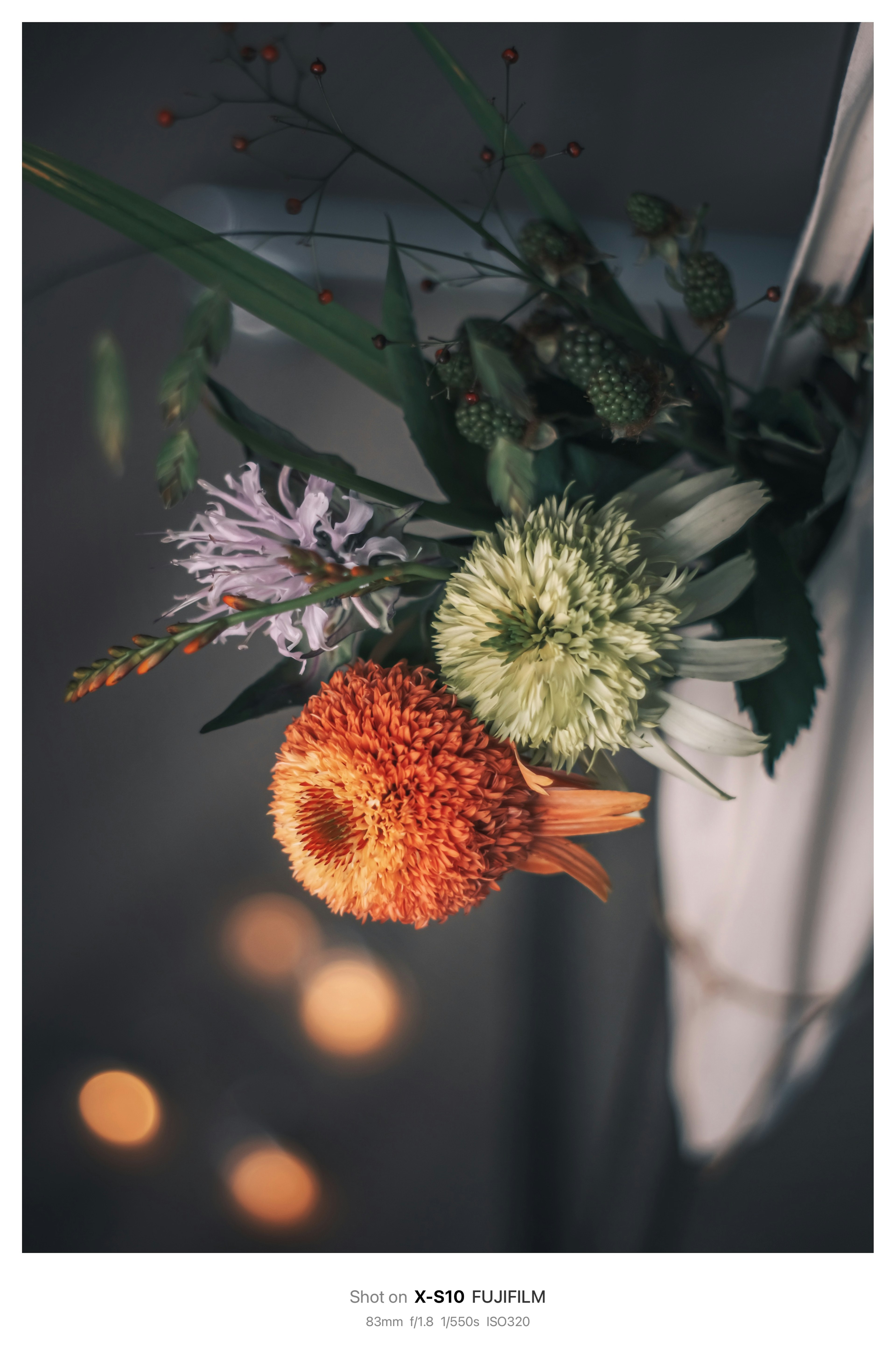 Primo piano di un bouquet di fiori con fiore arancione fiore verde e fiore viola su uno sfondo sfocato