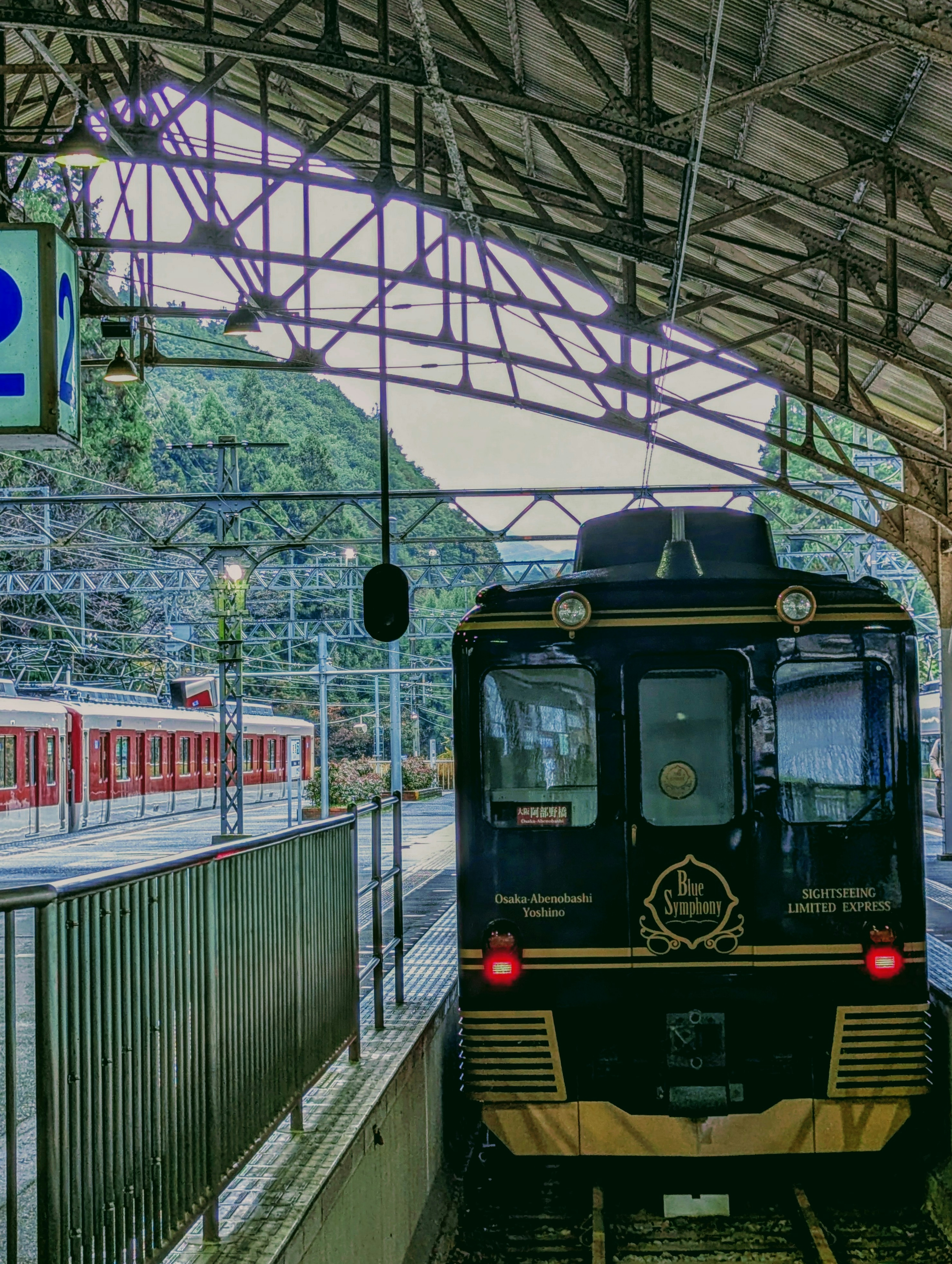 Blick auf einen schwarzen Zug und einen roten Zug an einem Bahnhof