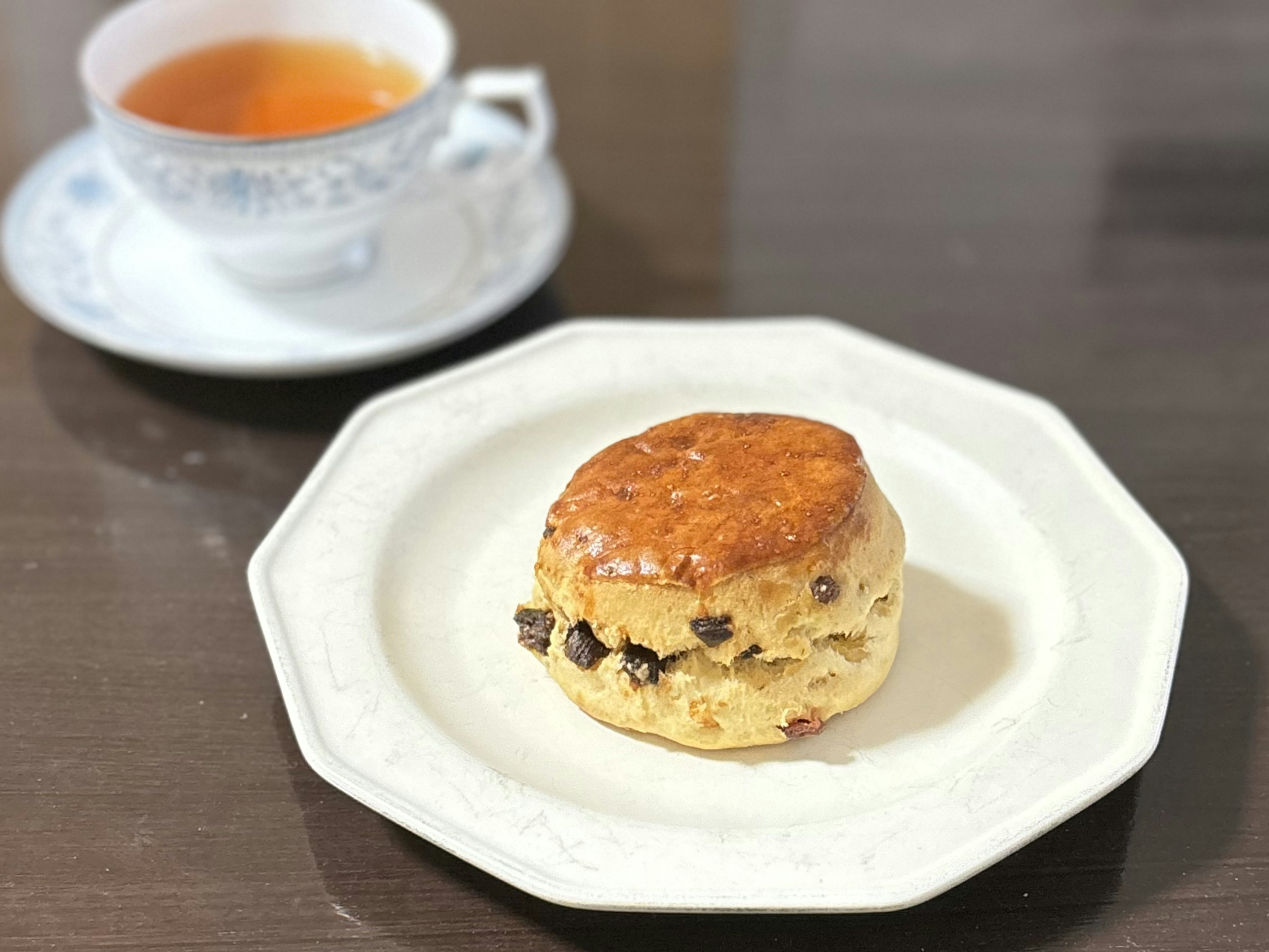 おしゃれな皿に置かれたチョコチップスコーンと紅茶